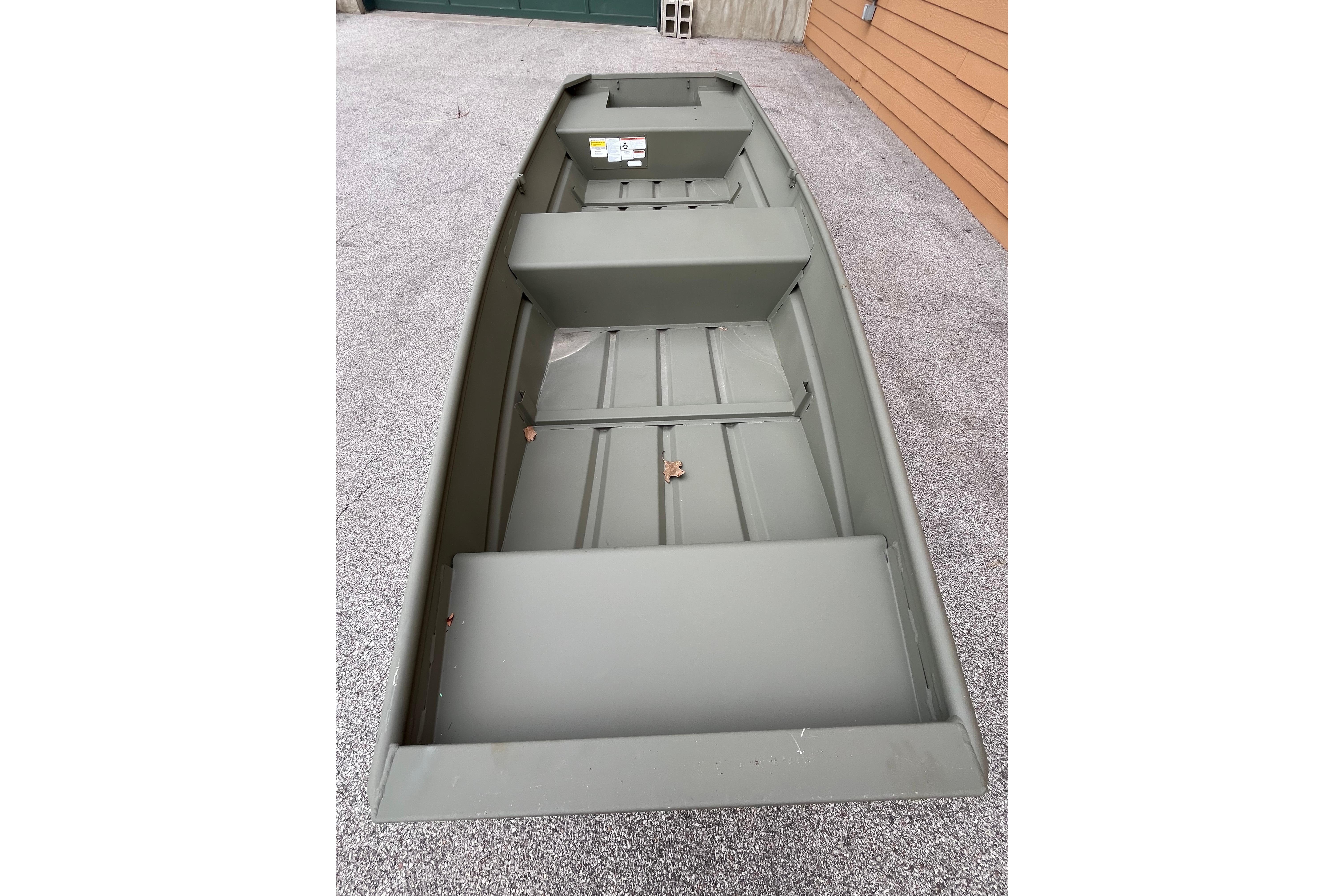 2026 Tracker Grizzly 14 Jon boat, olive green, parked on gravel surface.