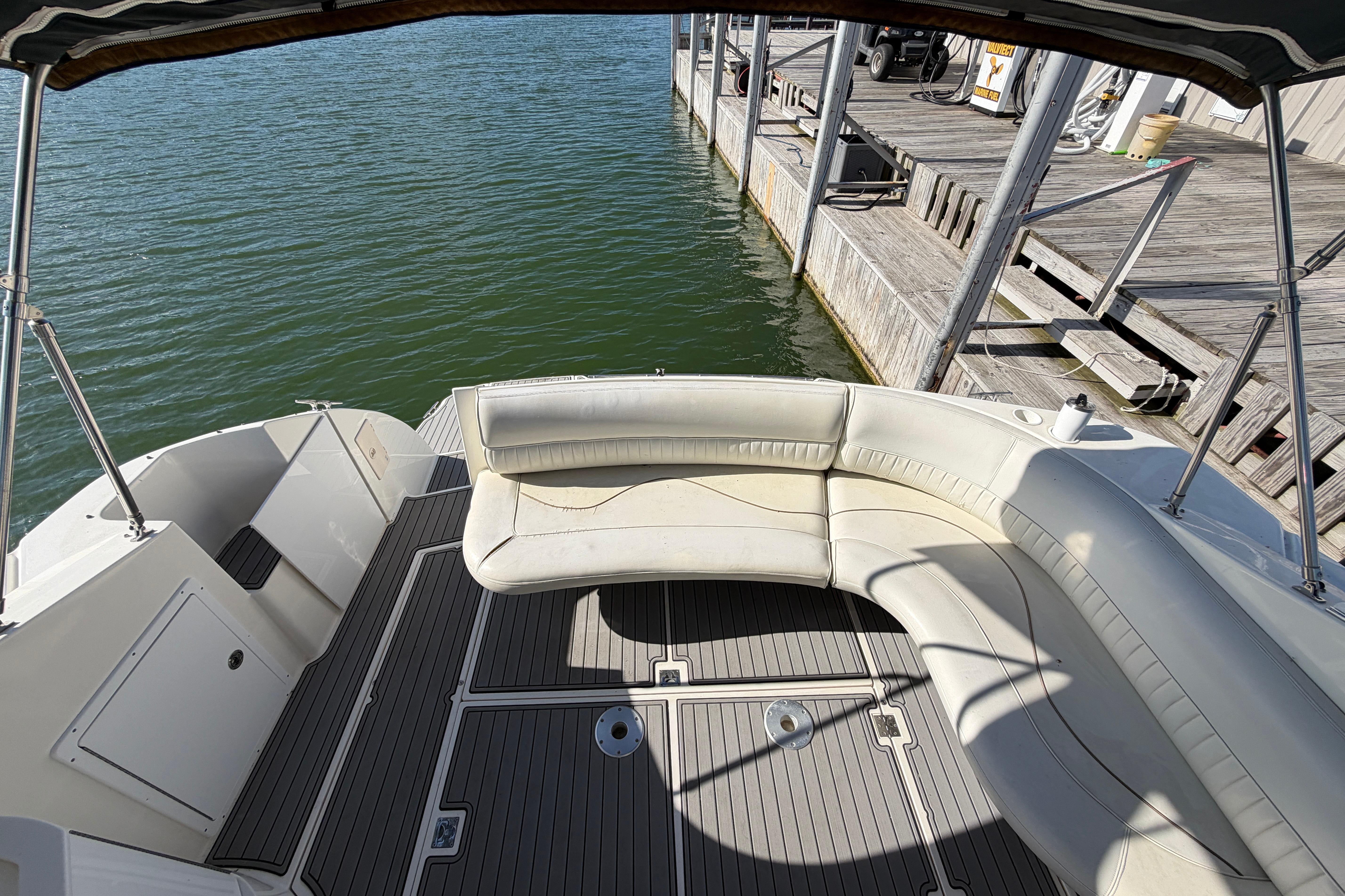 1997 Cruisers 3575 boat interior with white seating, docked by wooden pier.