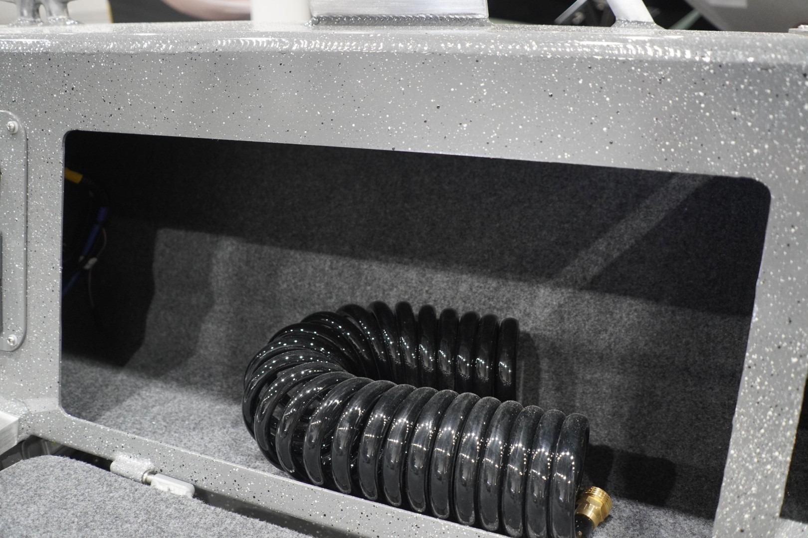 Interior compartment of 2026 Thunder Jet 209 Rush OT boat with coiled hose.