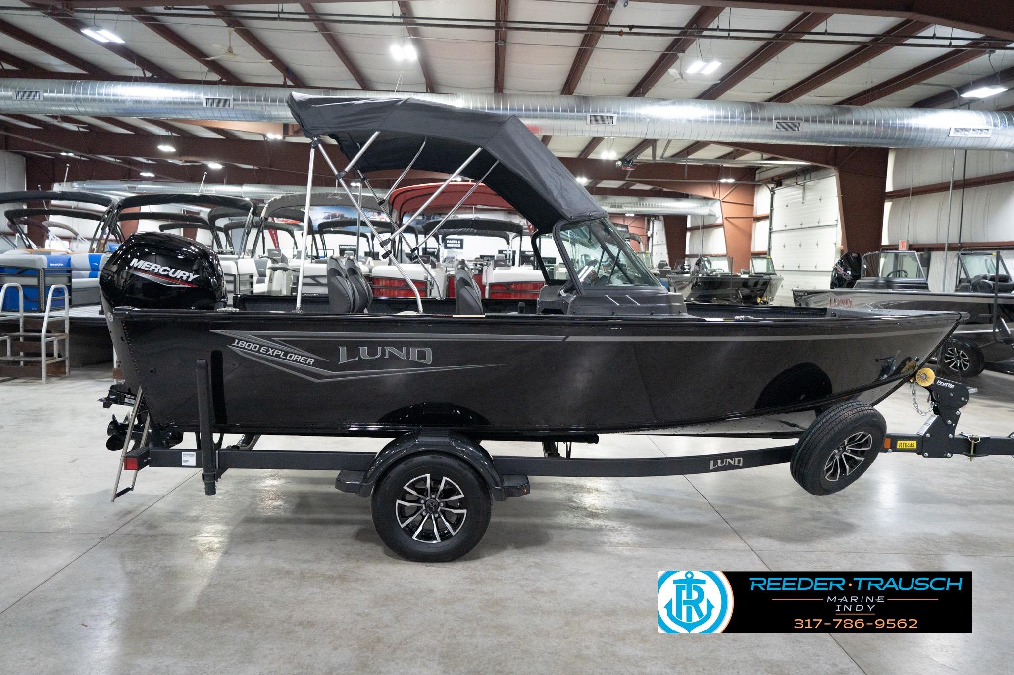 2026 Lund 1800 Explorer Sport boat in showroom, featuring Mercury engine and trailer.