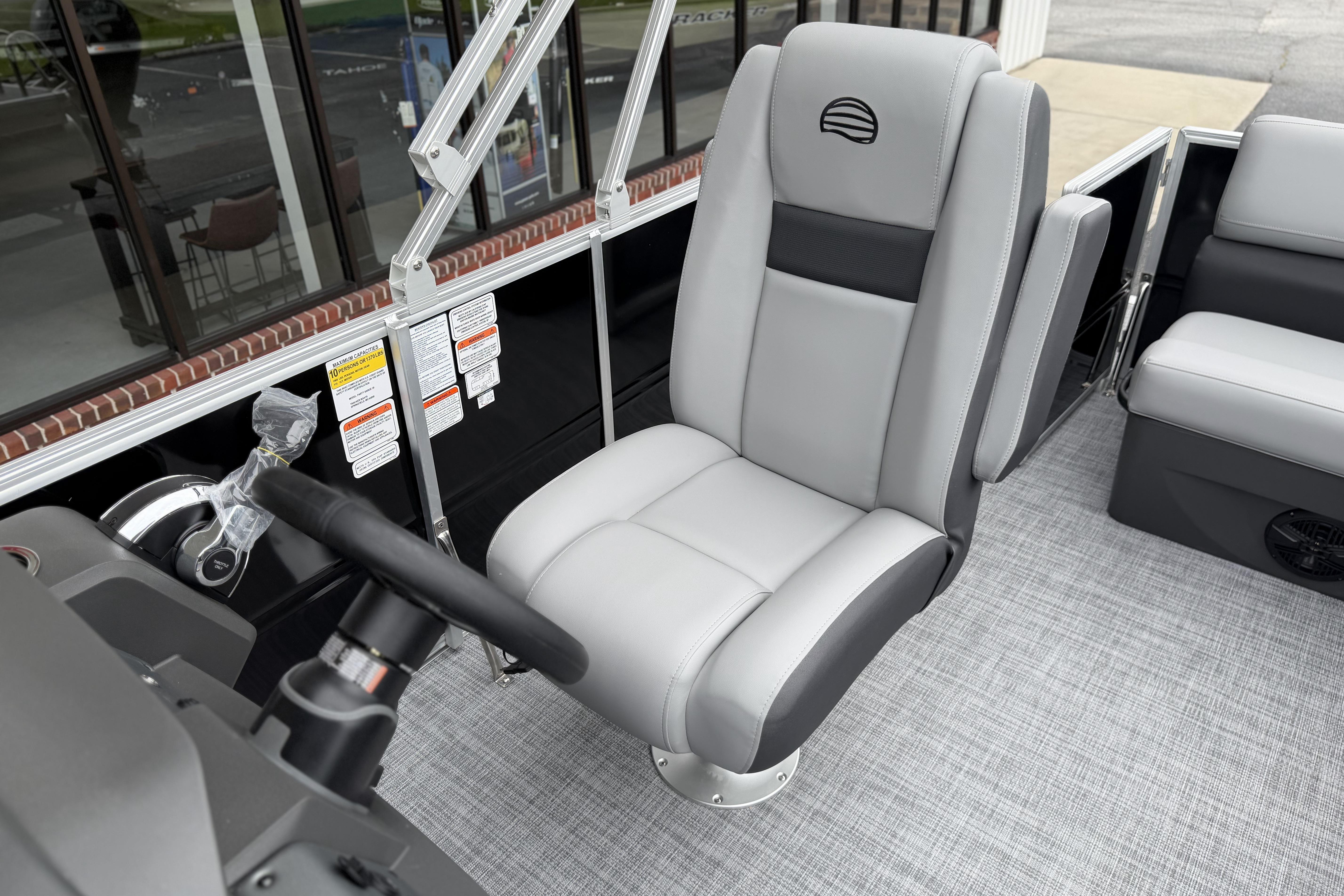 2026 Sun Tracker Party Barge 20 DLX interior with gray captain's chair and steering wheel.