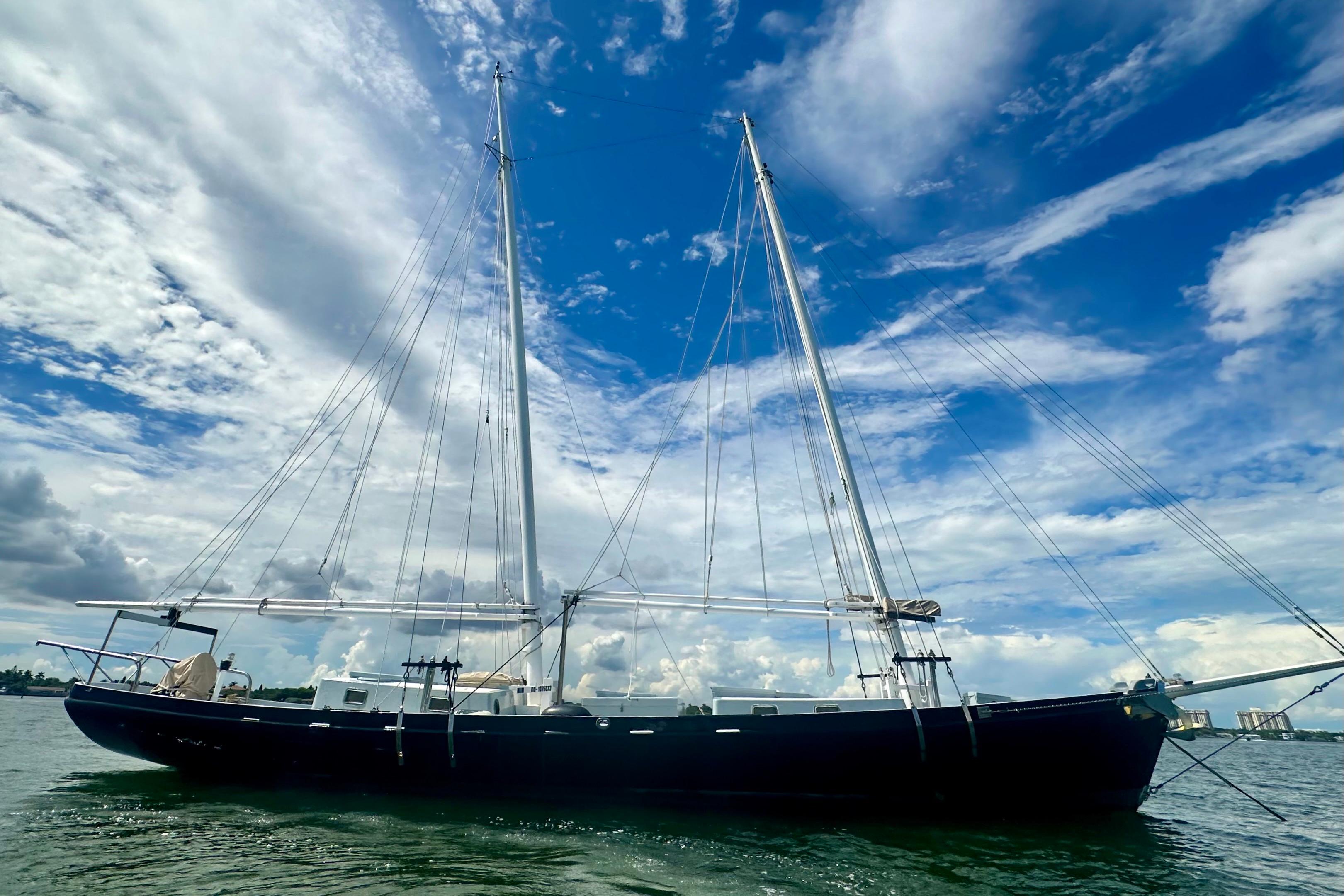 Schooner Leopard 1994 sailing under a vibrant blue sky with scattered clouds.