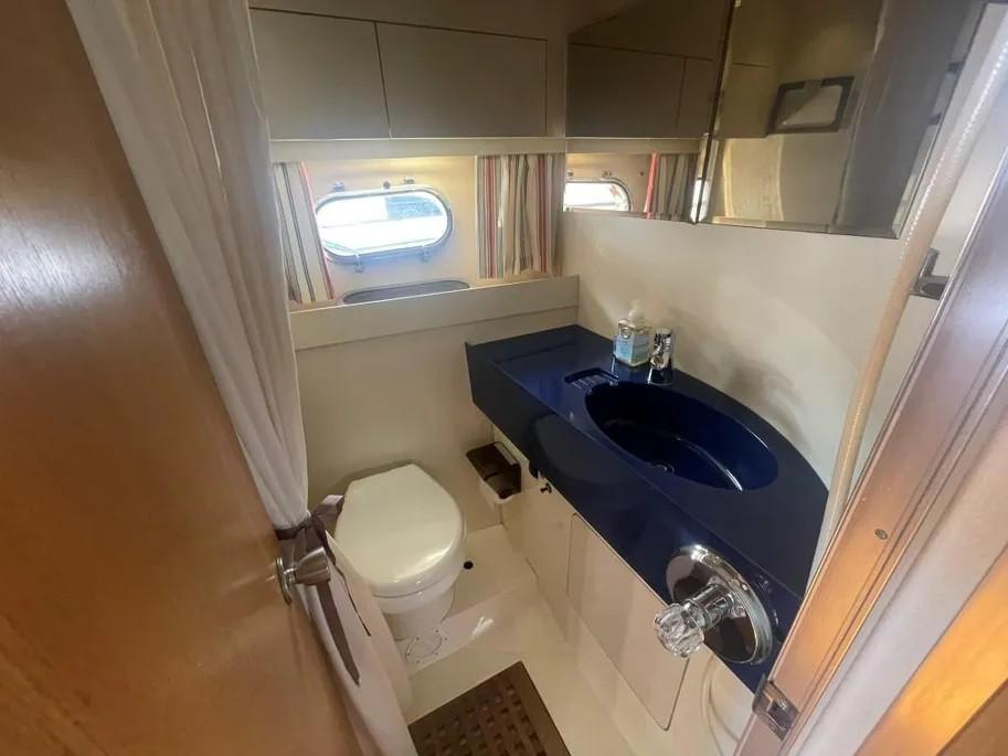 Bathroom interior of 1985 Princess Sedan Flybridge yacht with blue sink and porthole windows.