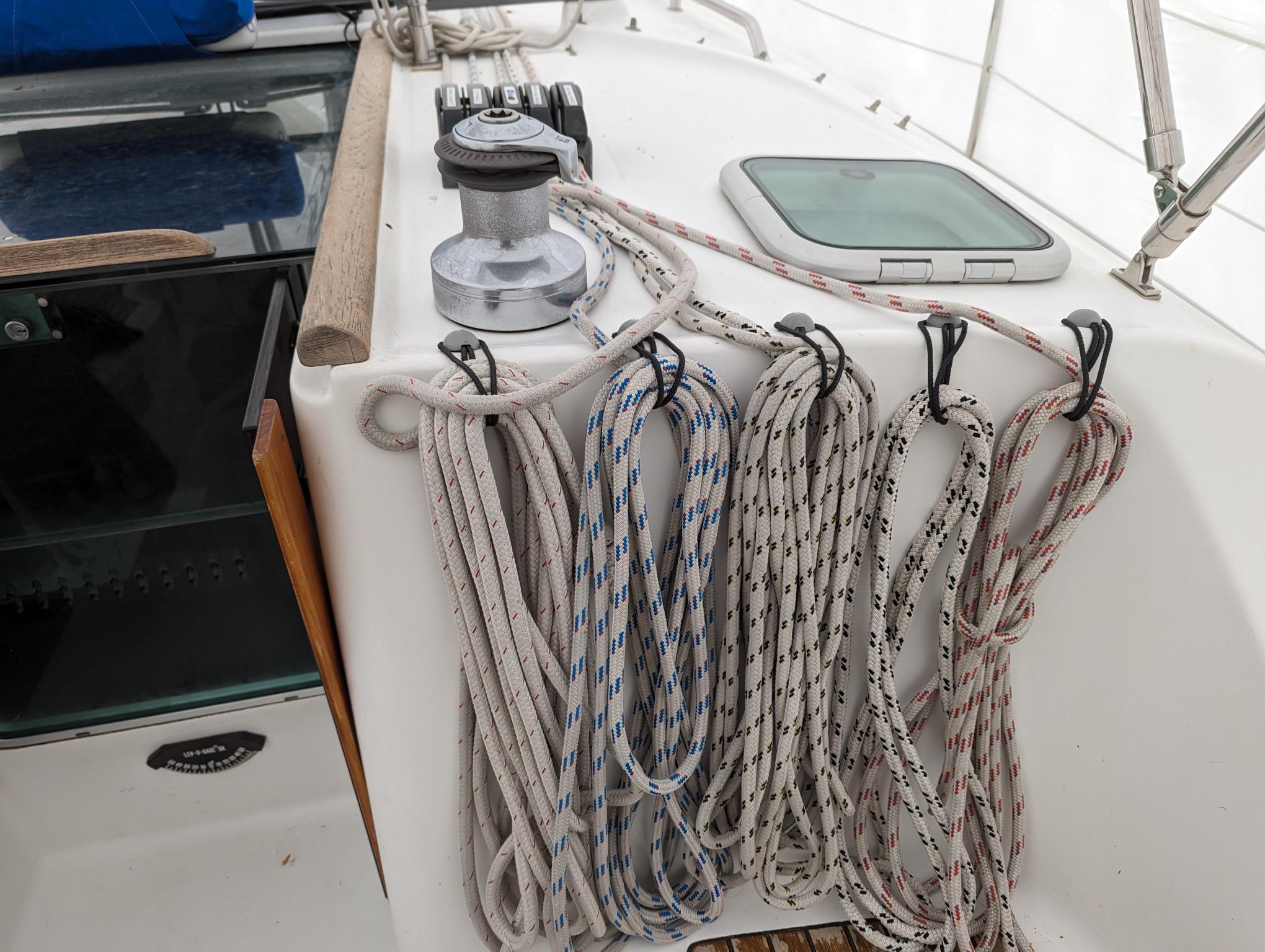 Deck of 2005 Beneteau 393 sailboat with neatly coiled ropes and winch.
