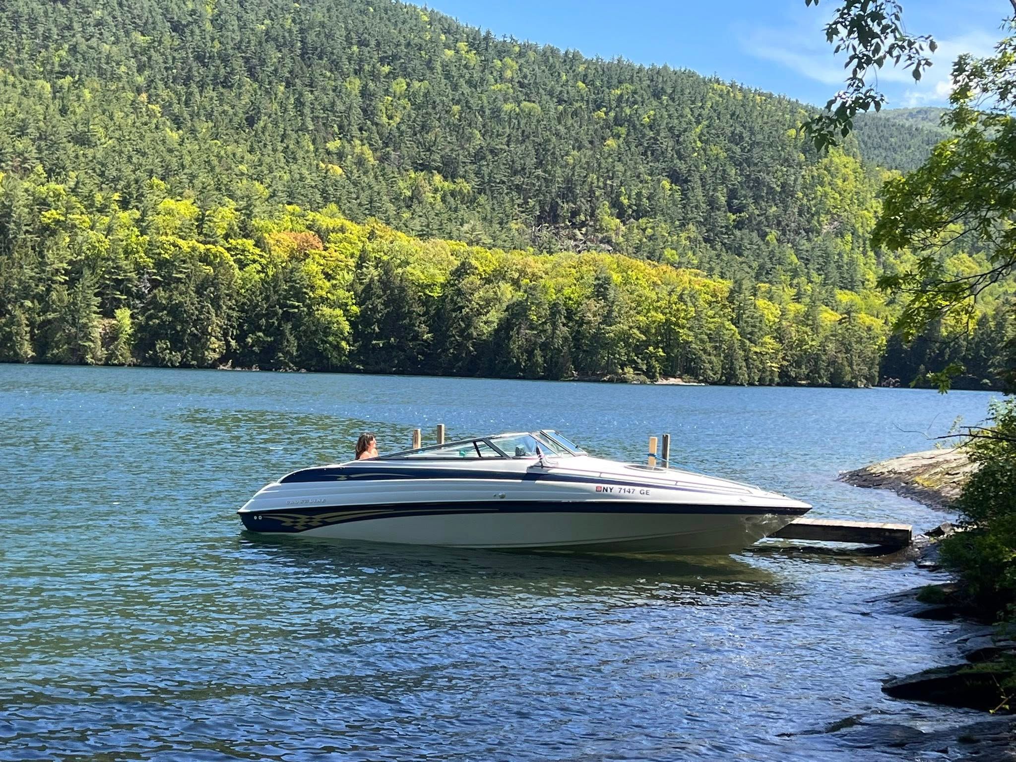 1999 Crownline 266 CCR boat on a serene lake.