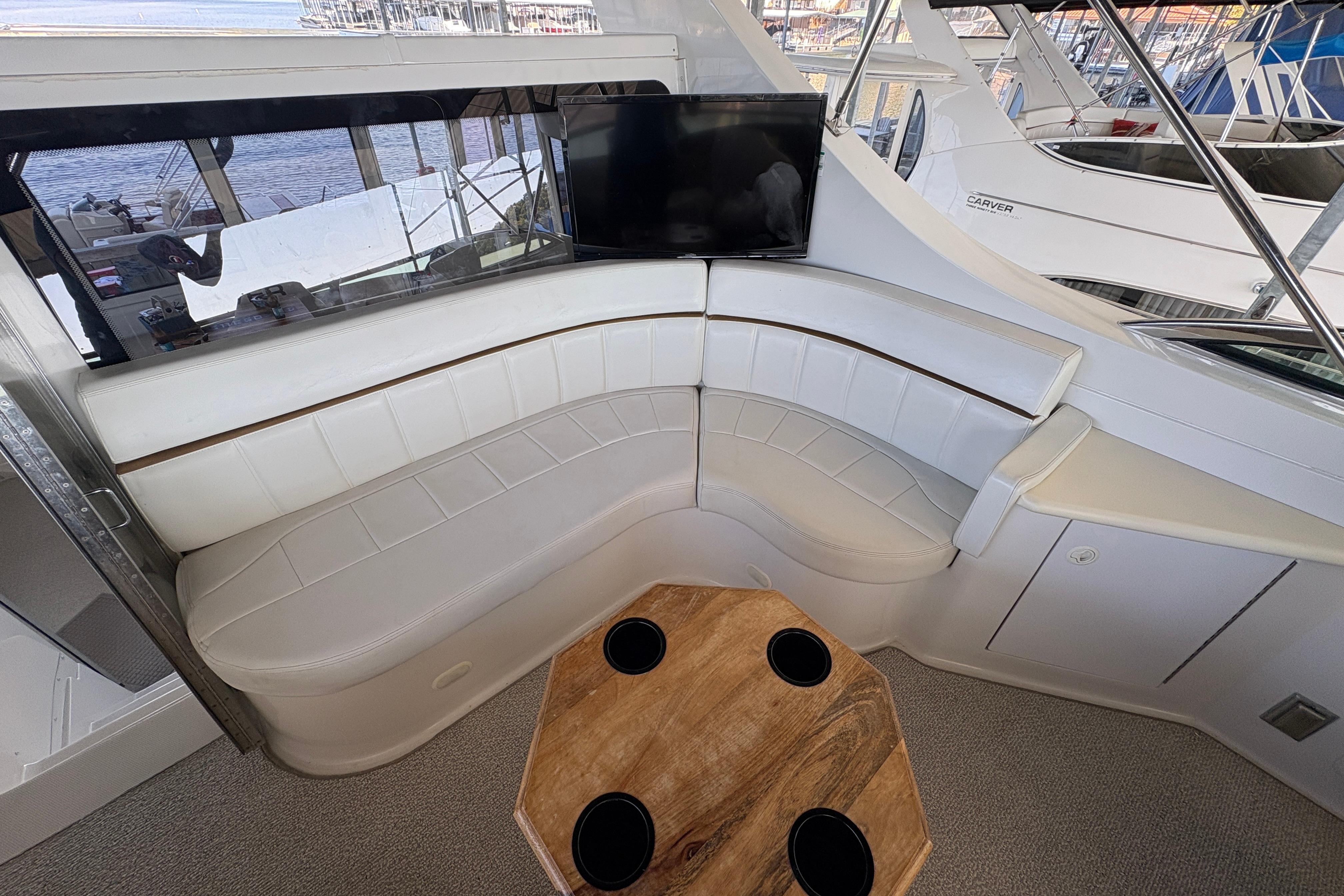 Luxurious interior of 2002 Carver 506 Motor Yacht with white seating and wooden table.