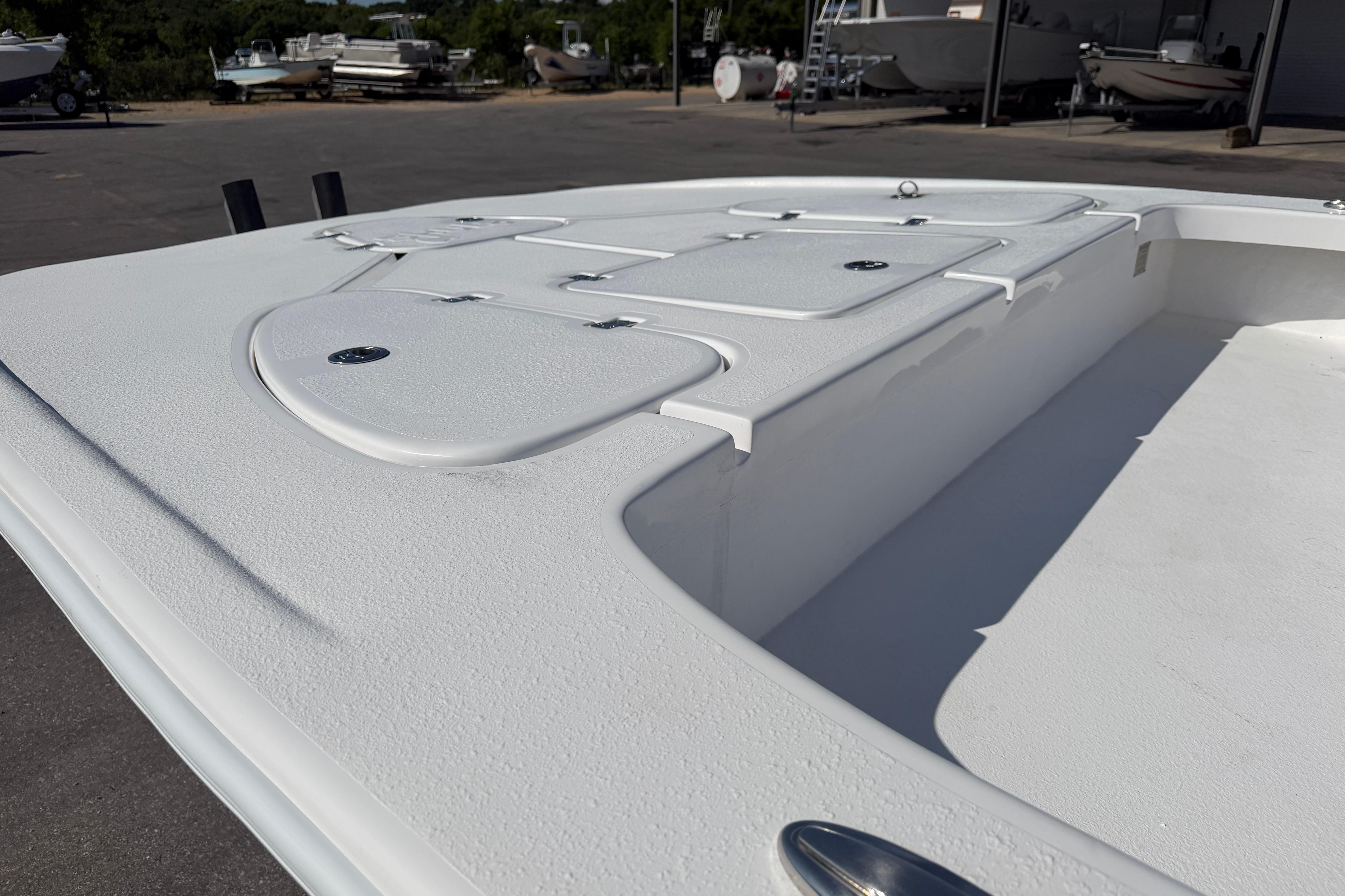 2026 Skuta 24 Cat boat deck with storage compartments, parked outdoors.