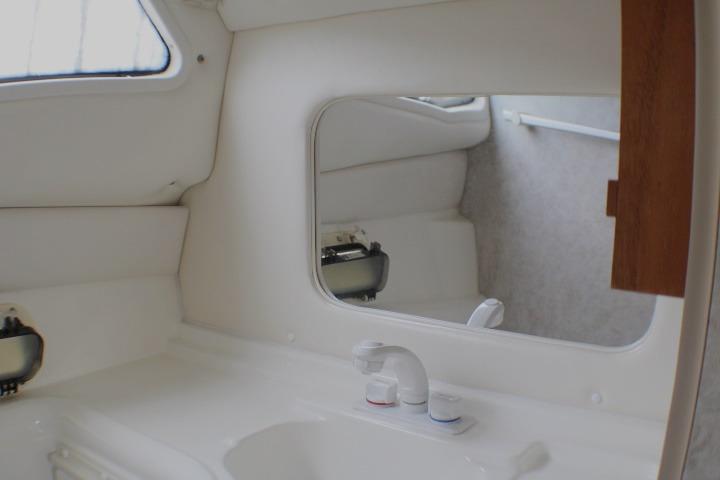 Interior of 1998 Bayliner 2655 Ciera Sunbridge boat bathroom with sink and mirror.