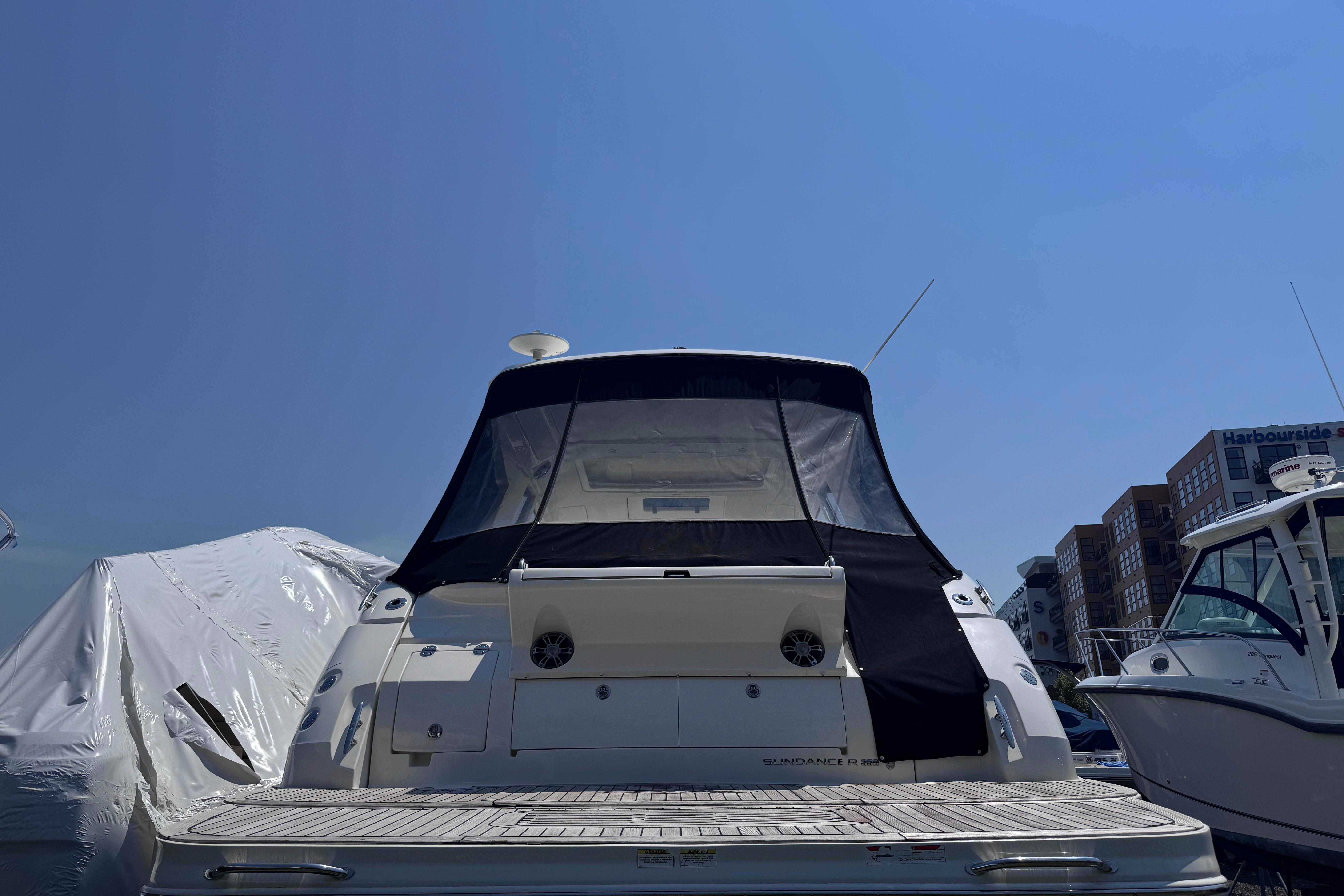2019 Sea Ray Sundancer 350 yacht docked, rear view with covered deck, clear blue sky.
