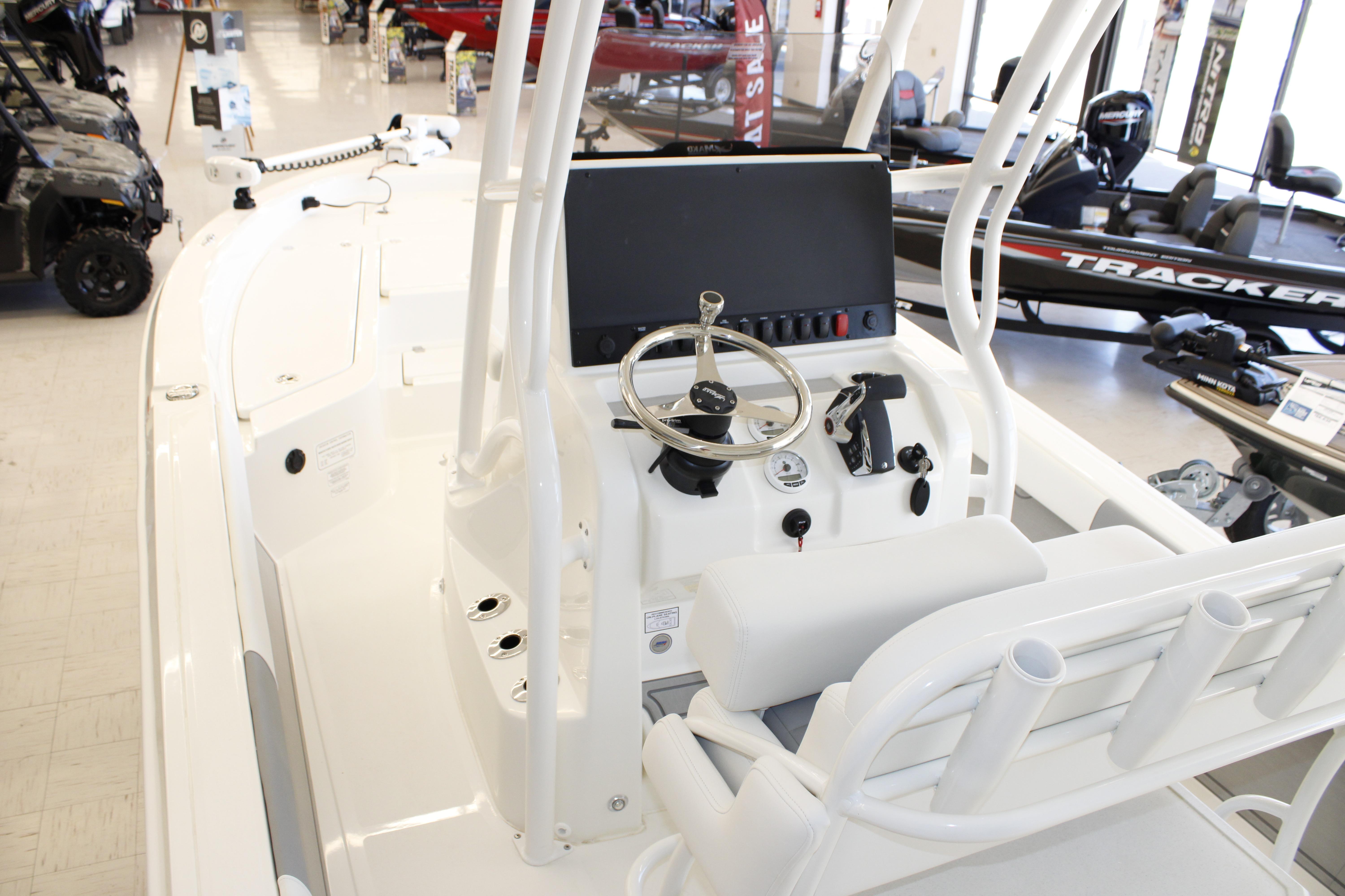 2026 Mako 24 APEX boat interior with steering console and seating in showroom.