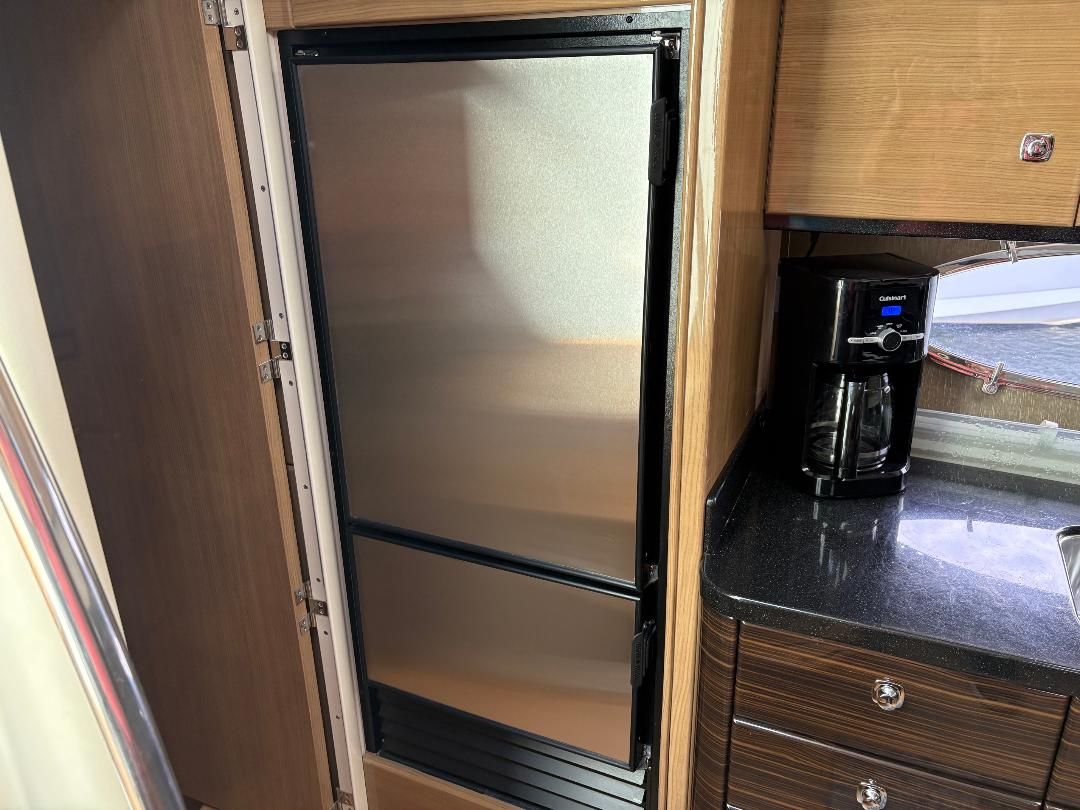 A modern galley with a large stainless steel refrigerator and a coffee maker on the countertop.
