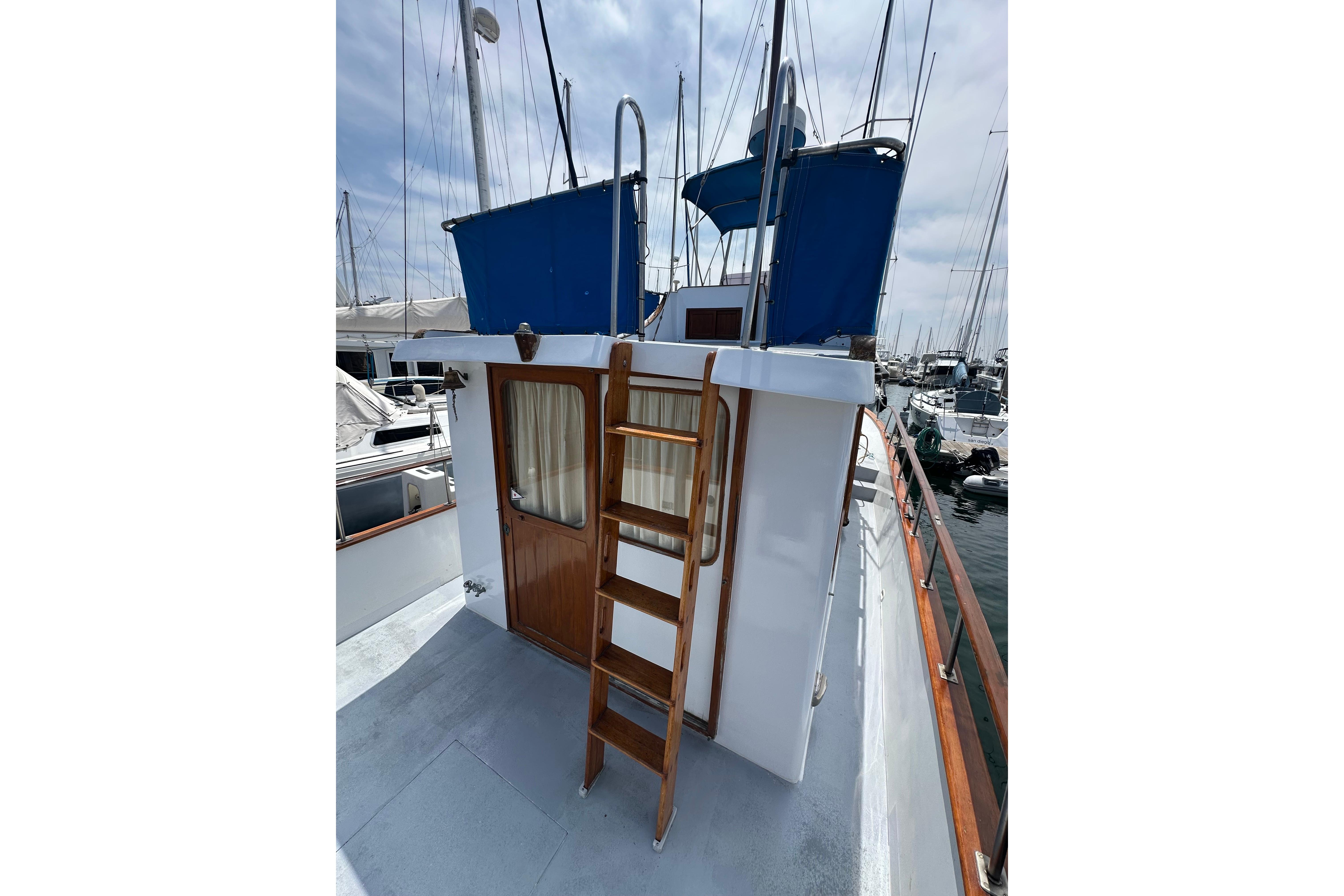 1973 CHB 33 boat with wooden ladder and blue canopy in marina.