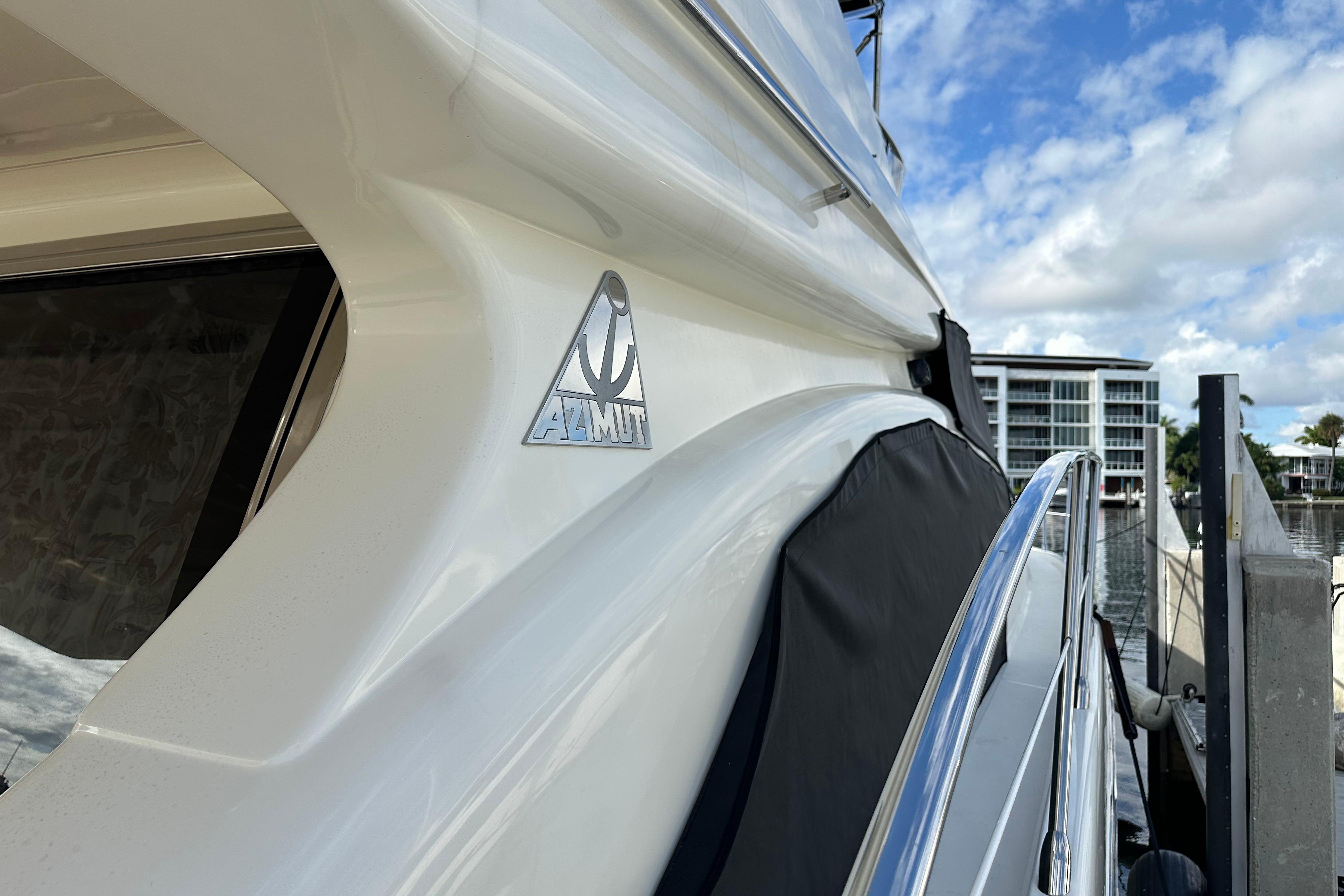 2004 Azimut 55E yacht docked, showcasing sleek design and logo under a partly cloudy sky.
