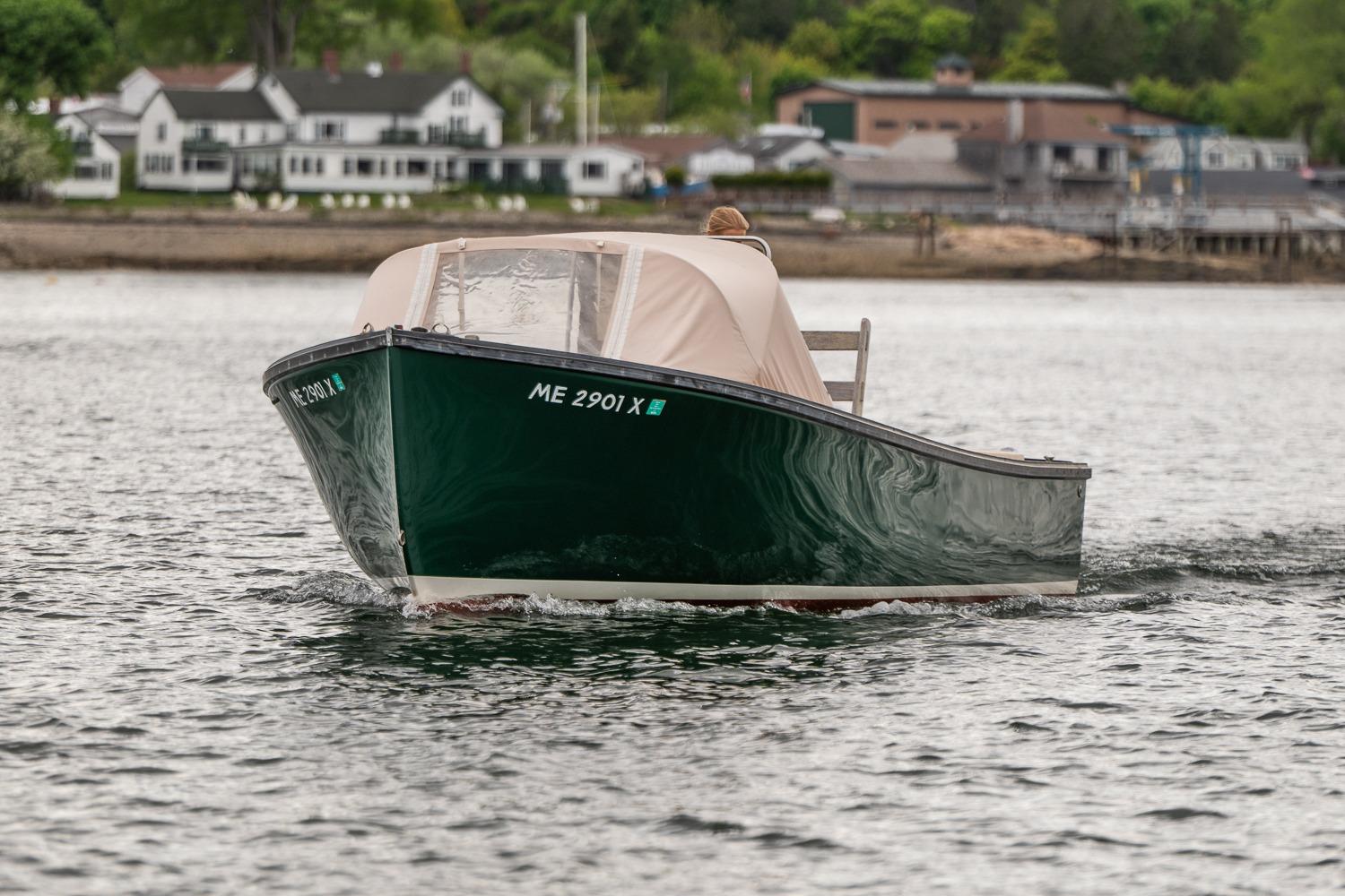 1989 Ellis 24 Open boat cruising on calm water near shoreline houses.