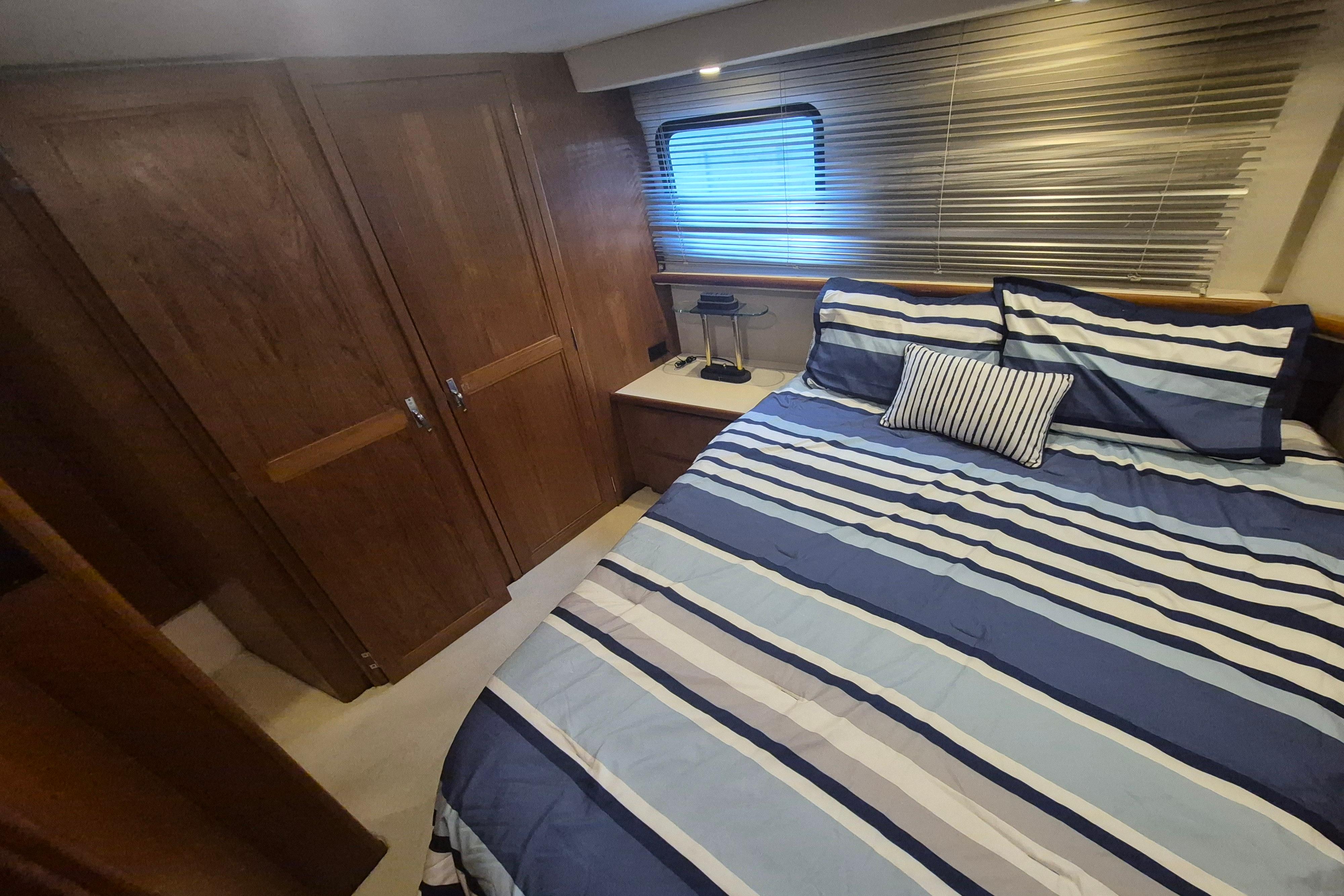 Cozy bedroom in 1993 Carver 350 Aft Cabin Motor Yacht with striped bedding.