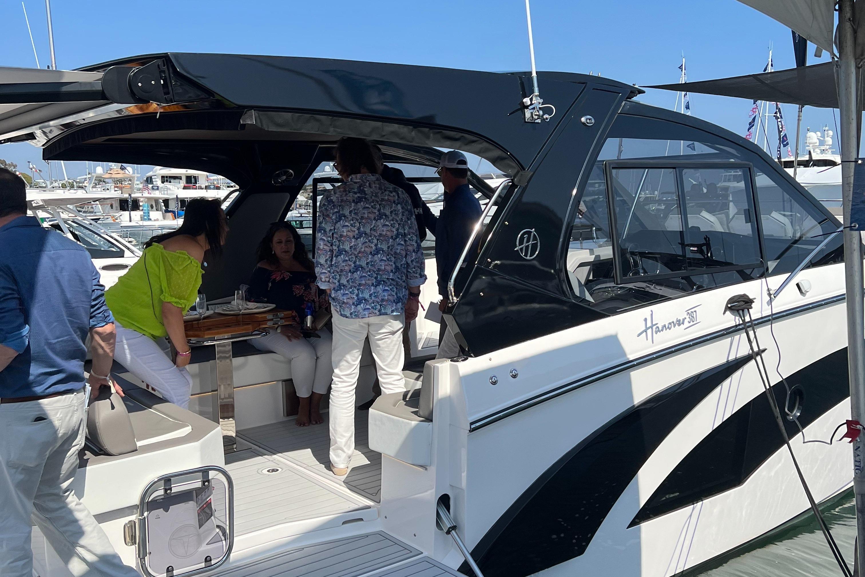 People socializing on a 2025 Hanover 387 yacht at a marina.