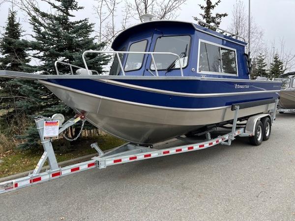 2024 Spartan 26 Maximus Pro XL boat on trailer, blue and silver design, parked outdoors.
