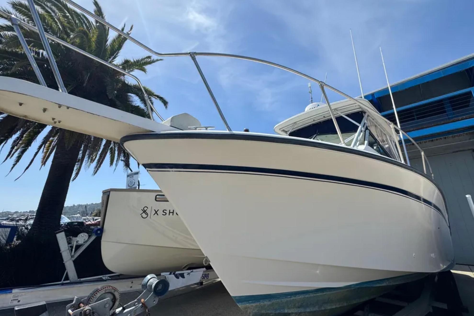 1990 Grady-White Marlin 280 boat on trailer, under clear blue sky, near palm tree.