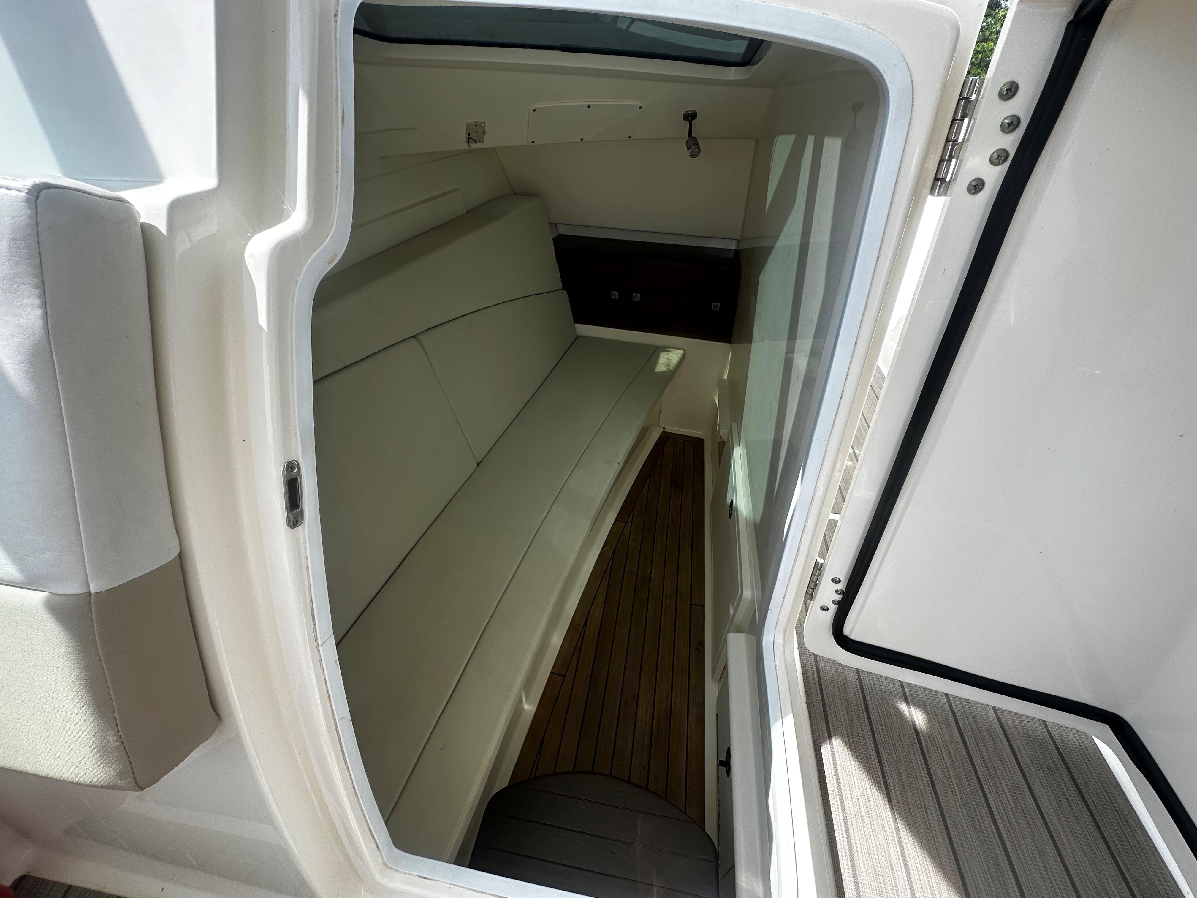 Interior cabin of 2016 Boston Whaler 320 Vantage boat, featuring seating and wood flooring.