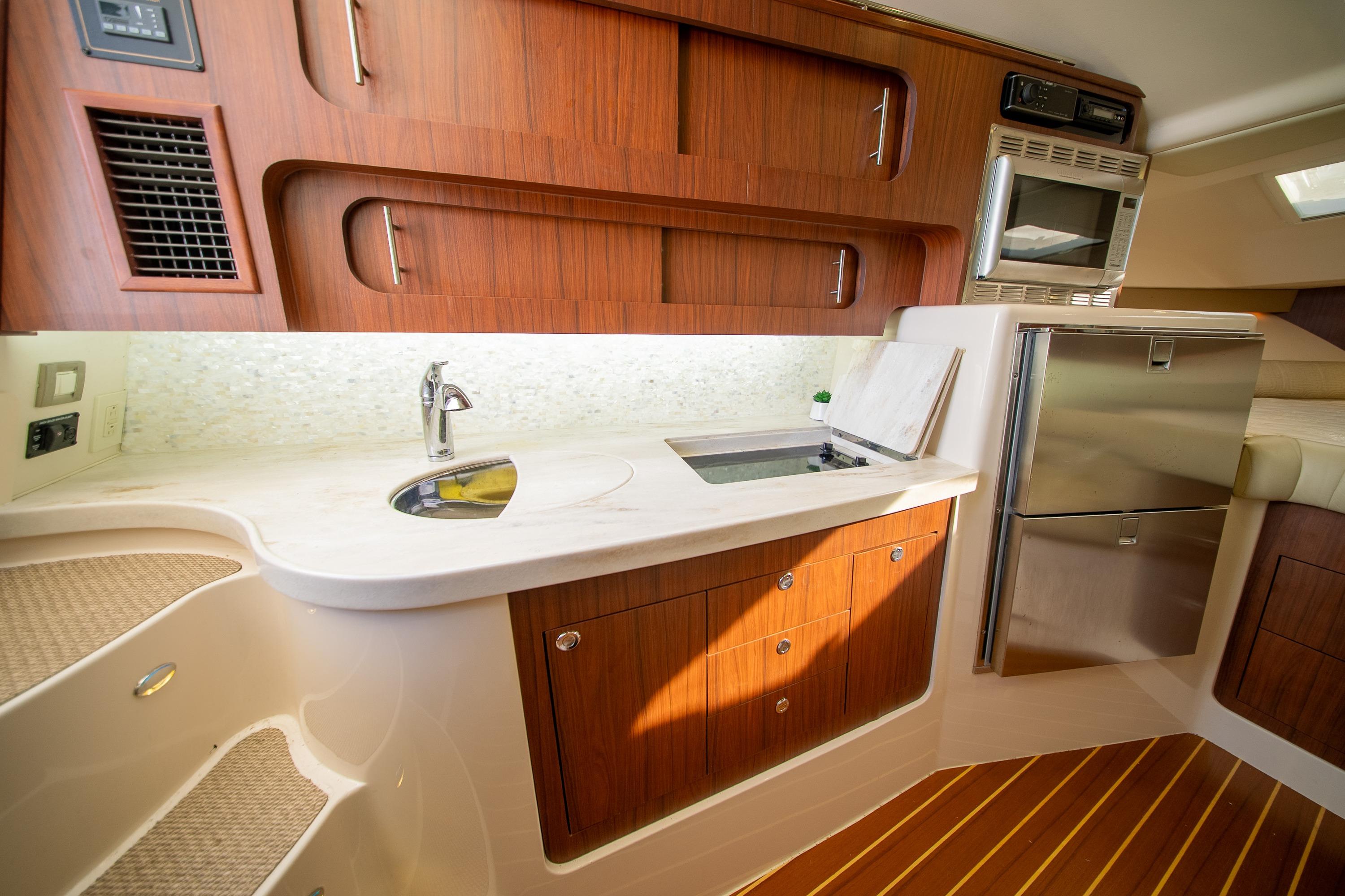 Luxurious 2015 Grady-White Express 370 yacht interior kitchen with wood cabinetry and modern appliances.