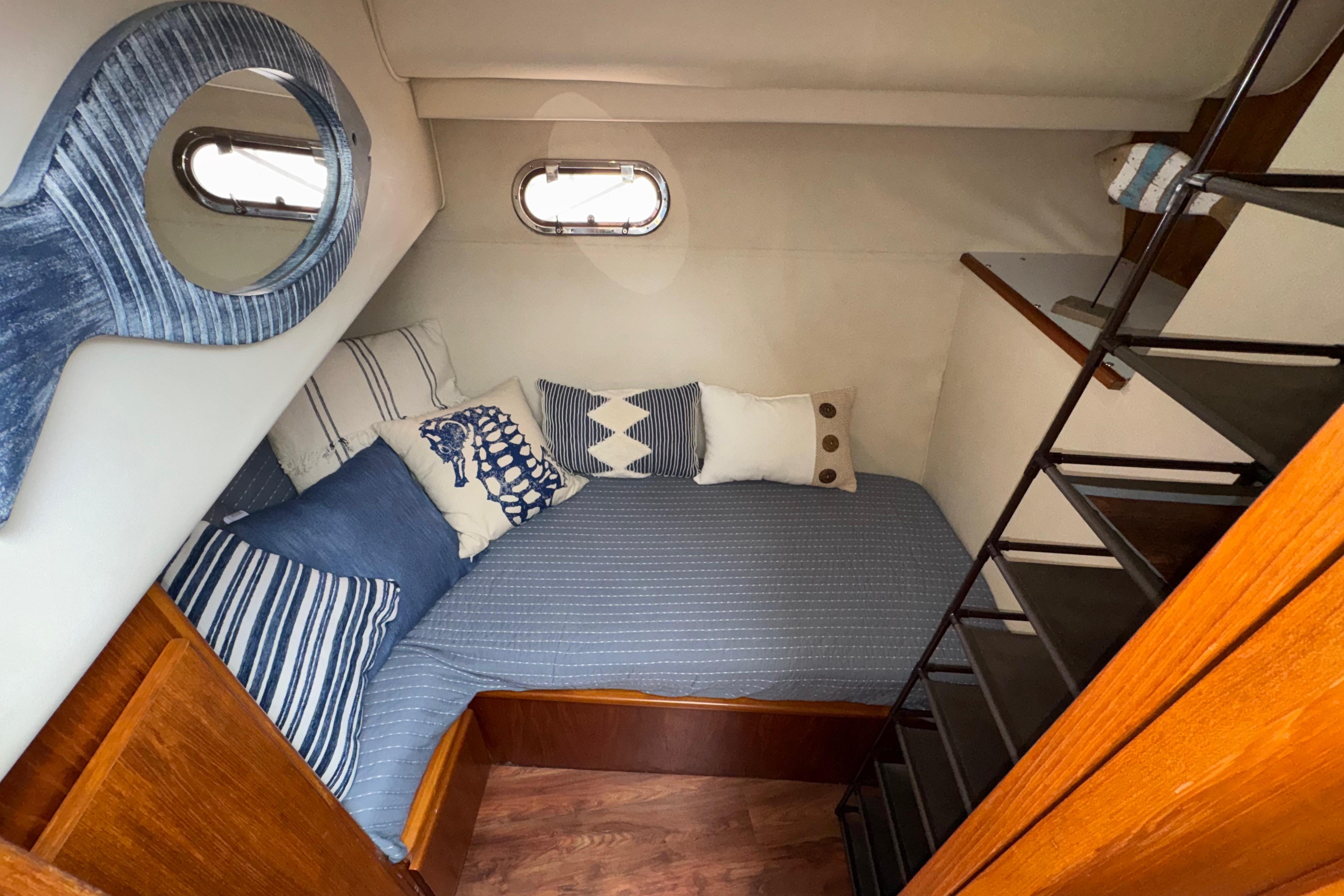 Cozy cabin interior of 1996 Carver 370 Voyager with nautical-themed bedding and wooden accents.