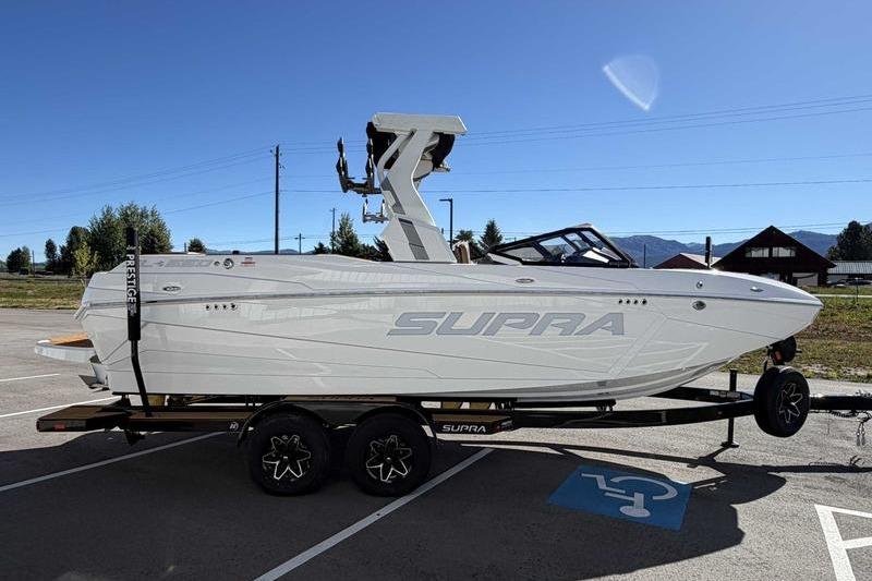 2026 Supra SL boat on trailer in parking lot under clear blue sky.