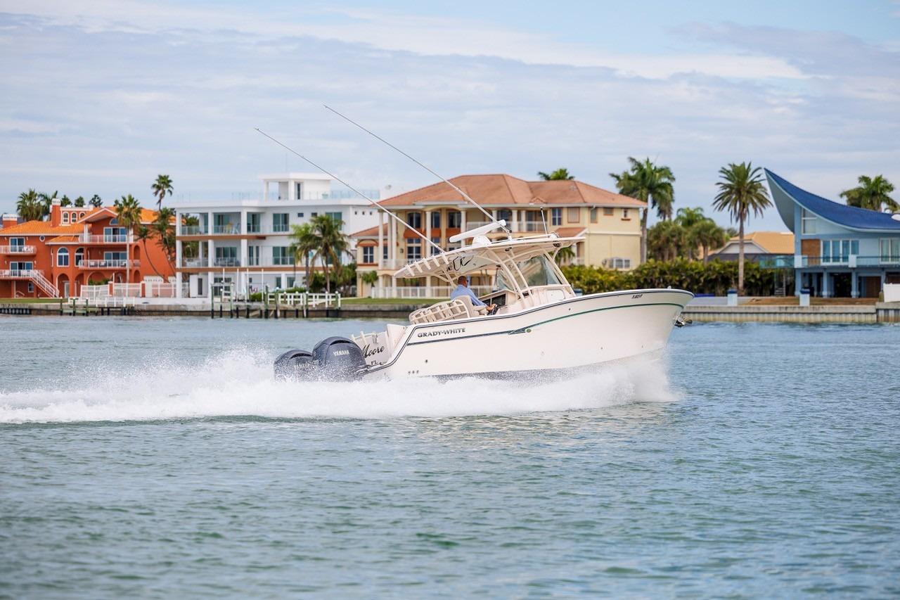 2014 Grady-White Canyon 336 boat cruising near colorful waterfront homes.