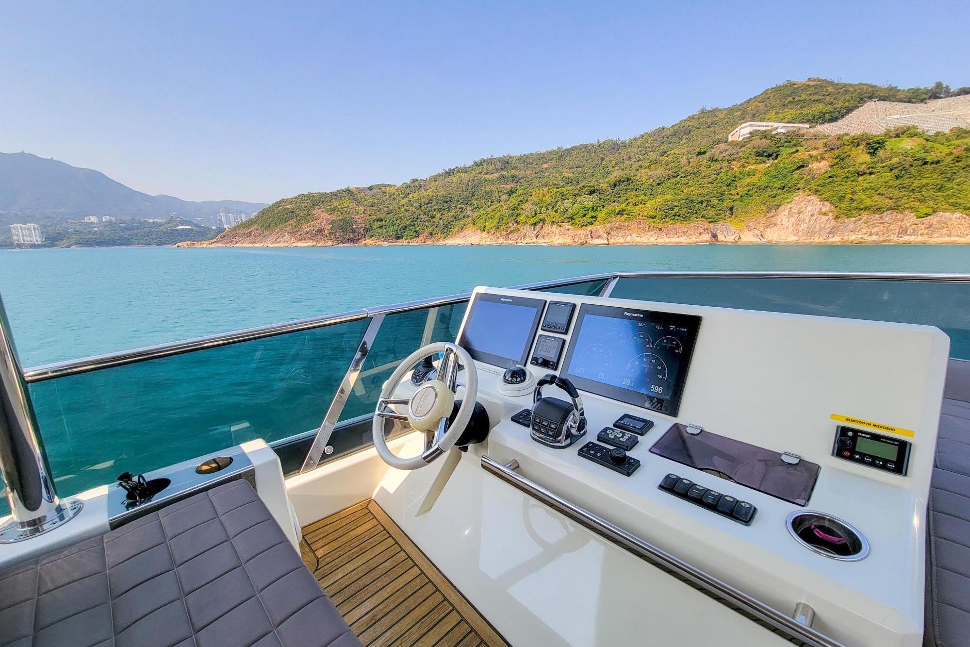 Luxurious 2019 Prestiage 630 yacht helm with scenic coastal view.