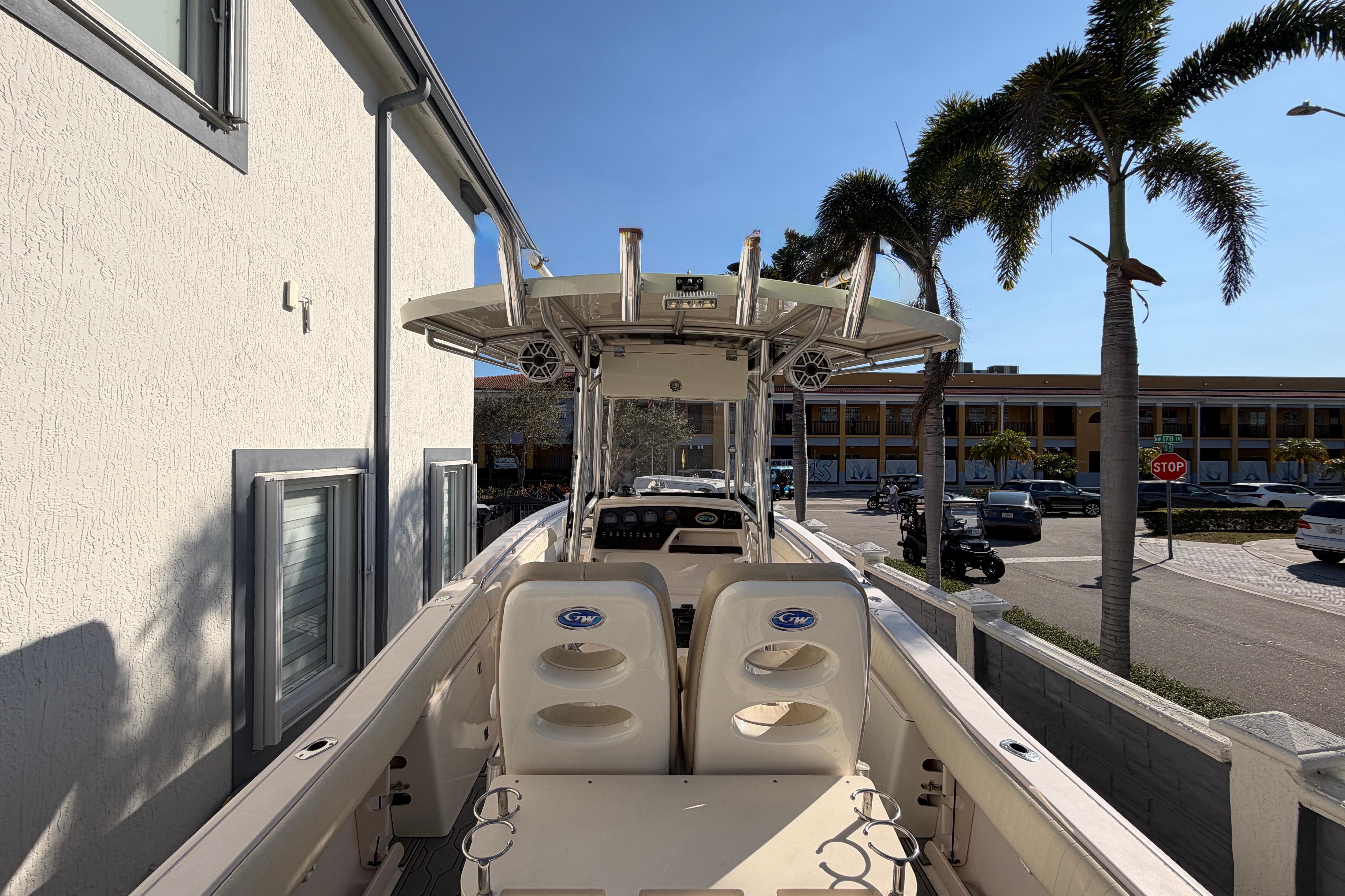 2004 Grady White 273 boat docked near palm trees and building.