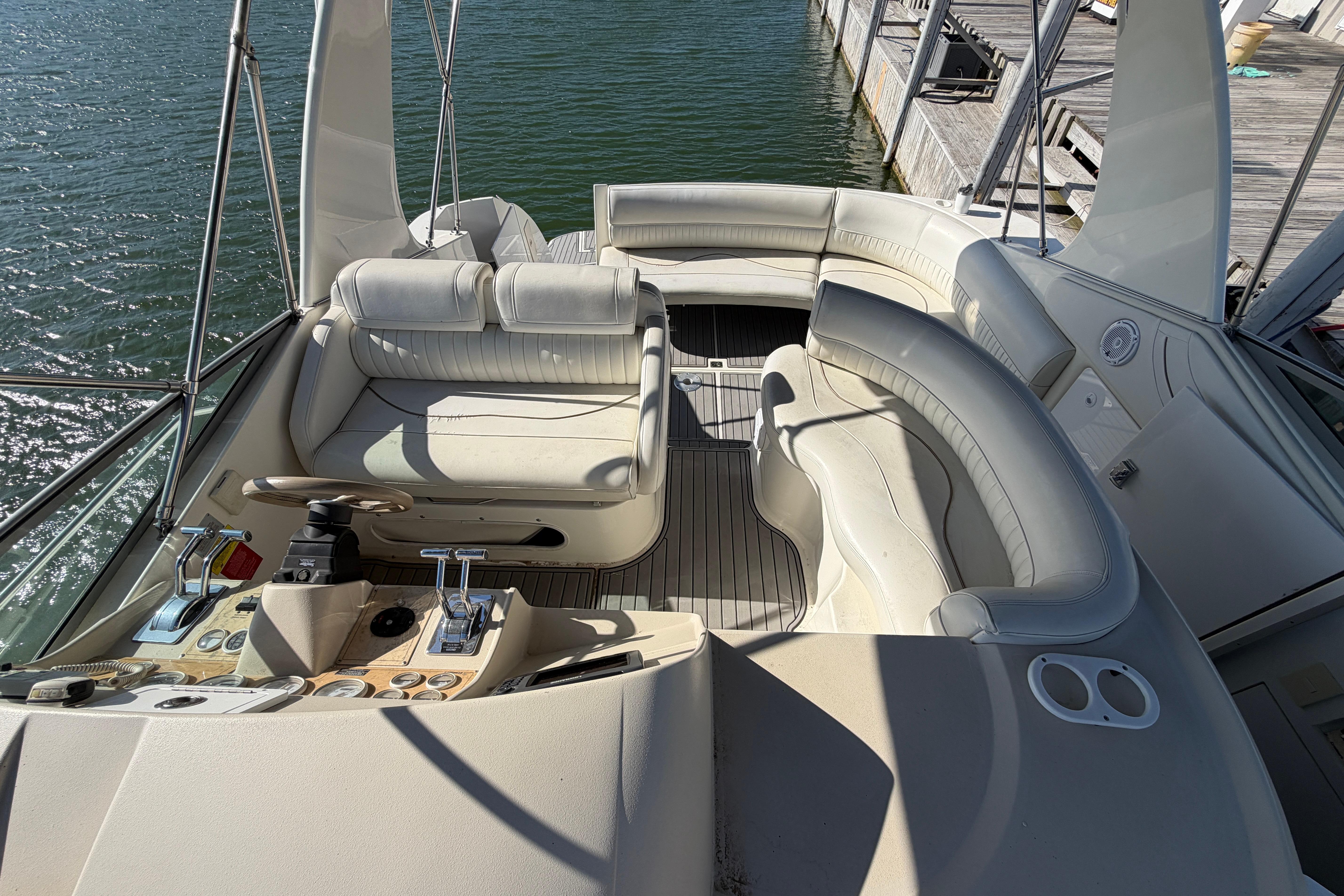 1997 Cruisers 3575 yacht interior with white seating and control panel, docked by the water.