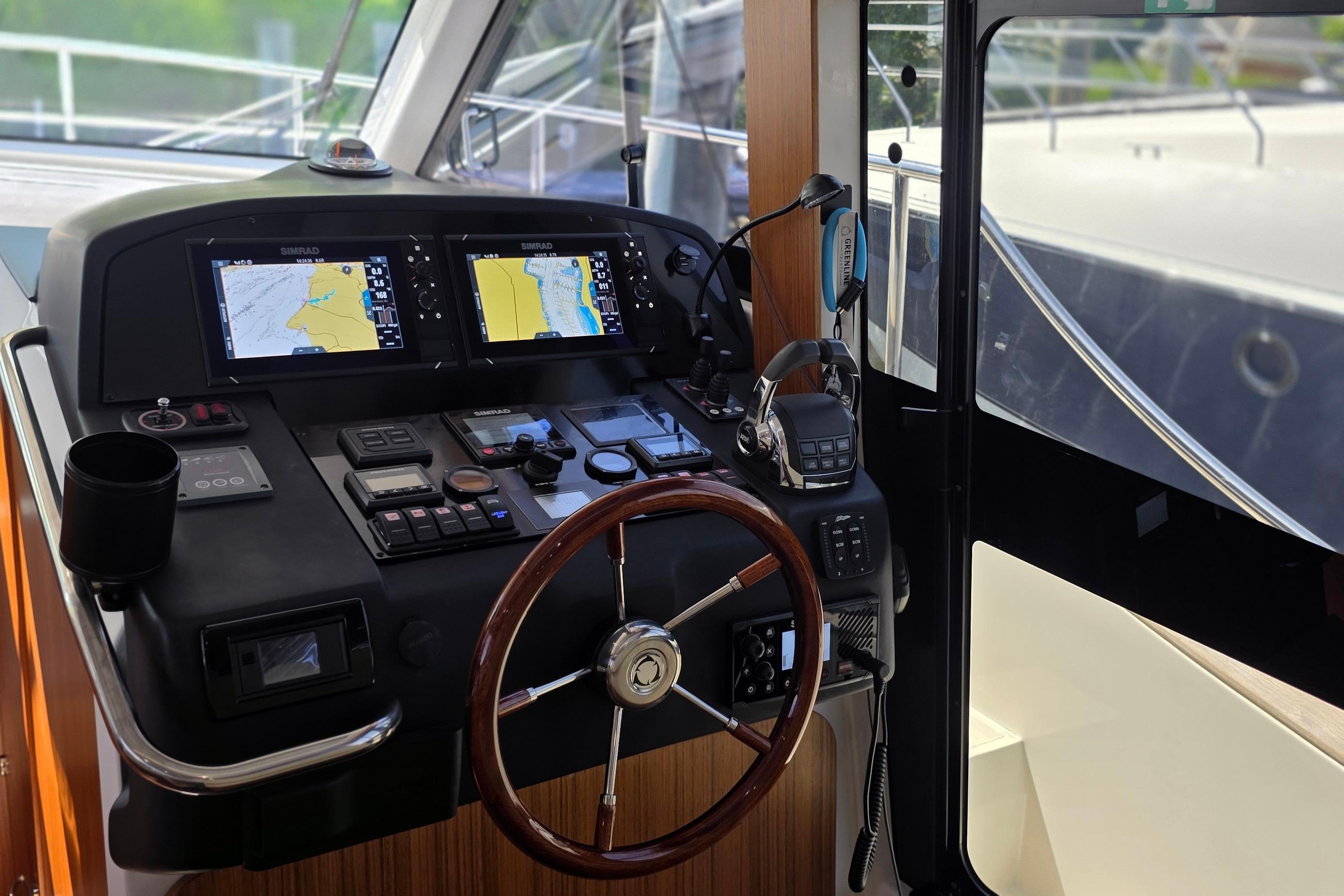 Cockpit of 2023 Greenline 40 yacht with navigation screens and steering wheel.