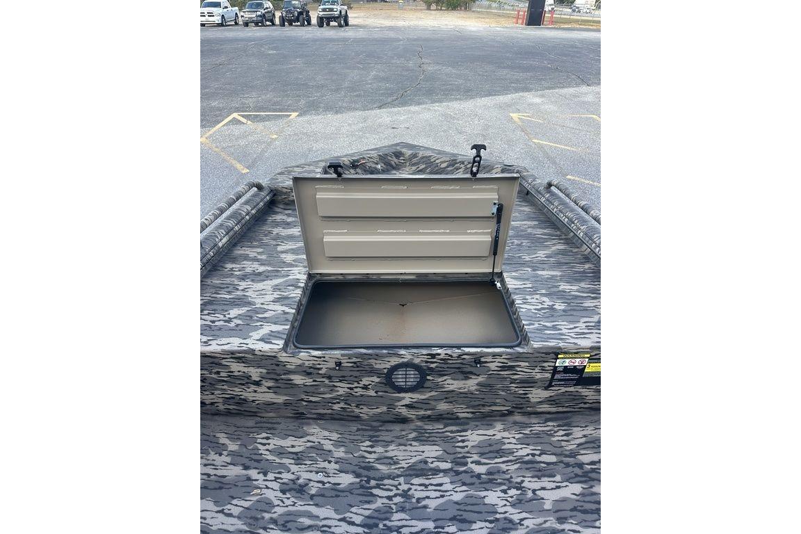 2025 Havoc 1860 boat with open storage compartment, camo pattern, parked in a lot.