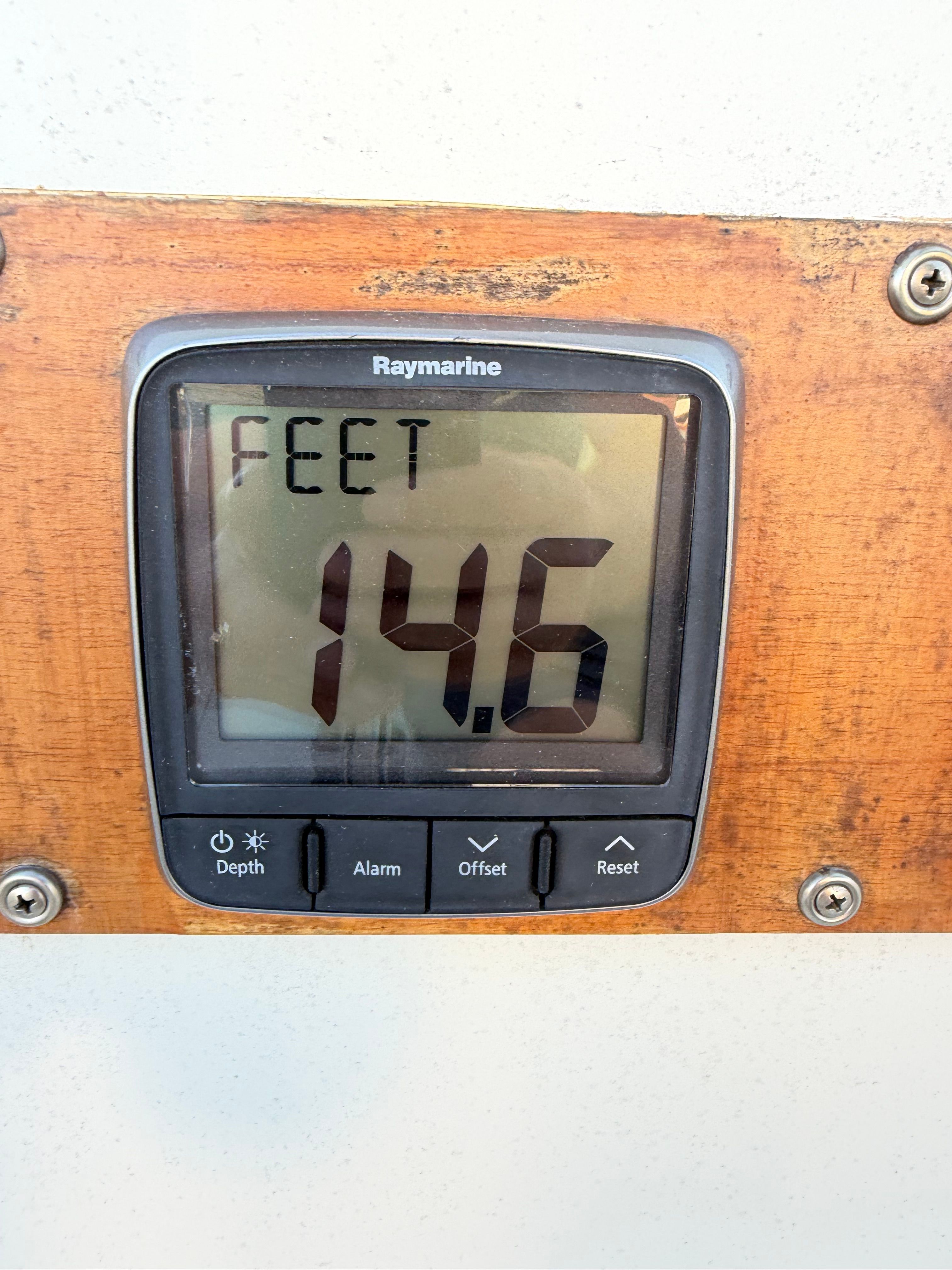 A Raymarine depth gauge displays 14.6 feet, mounted on a wooden panel.
