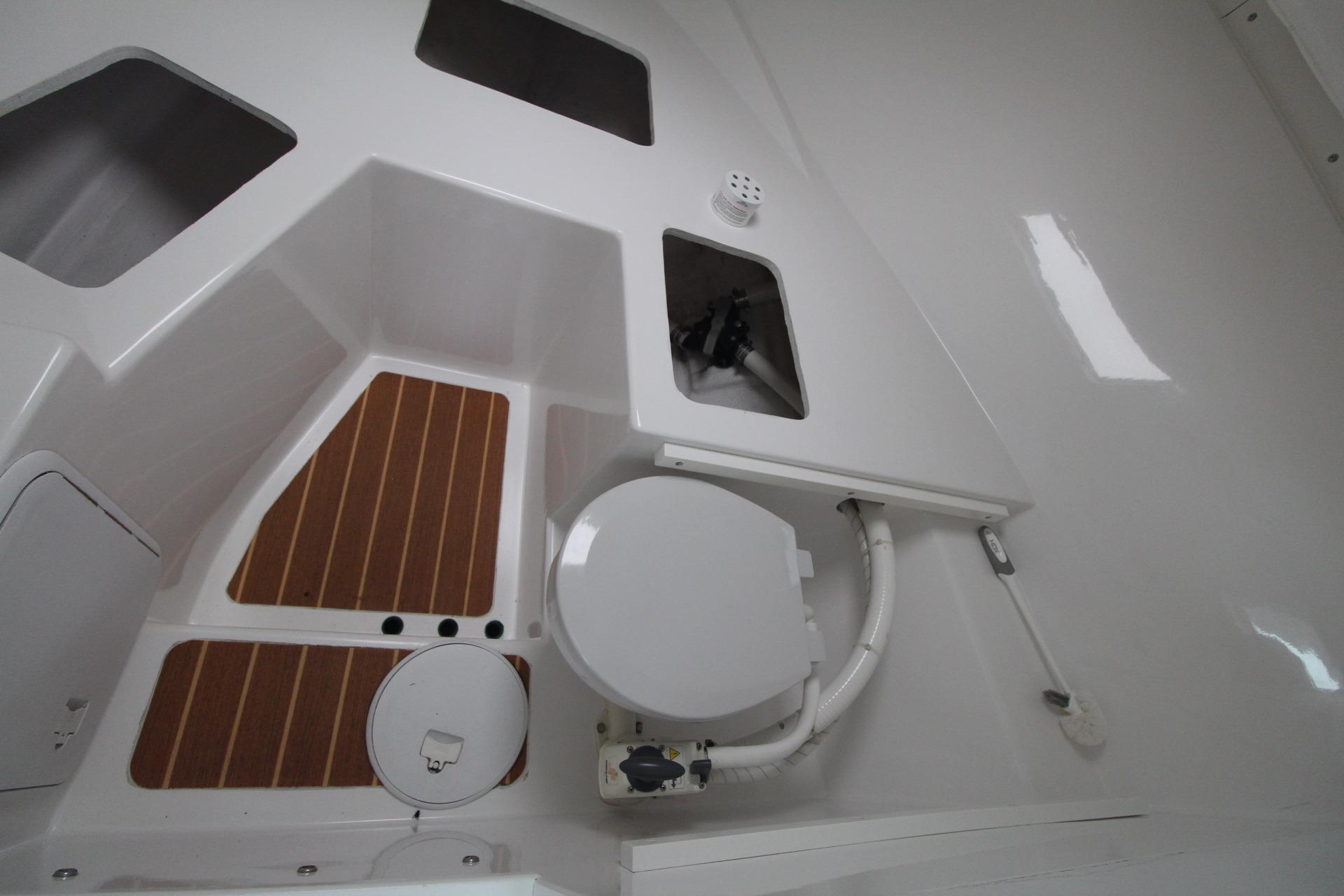 2014 Steiger Craft 26 Miami boat interior with toilet and wooden flooring.
