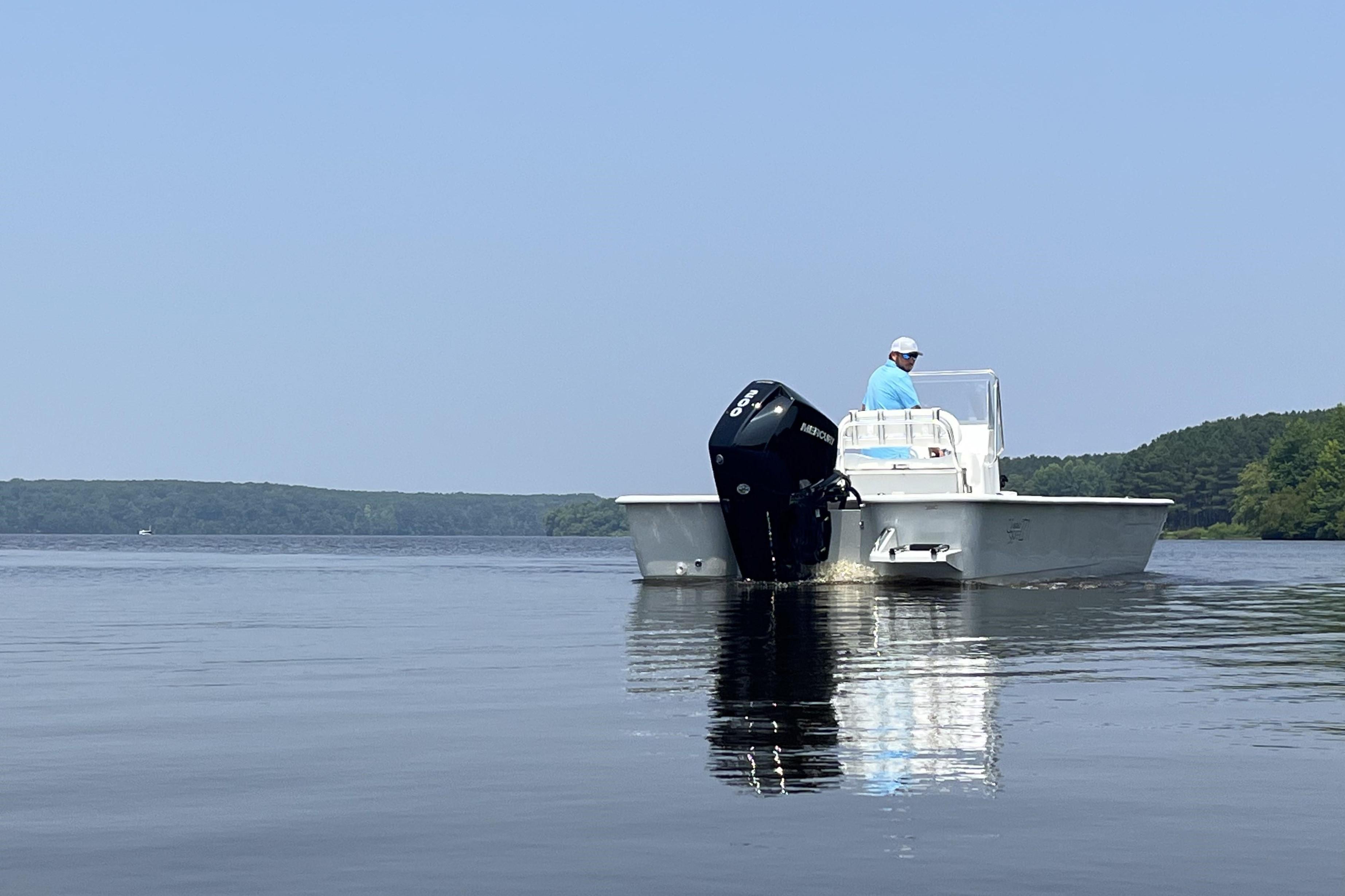 2024 Coastal Skiff 271 boat on calm water with a person at the helm.