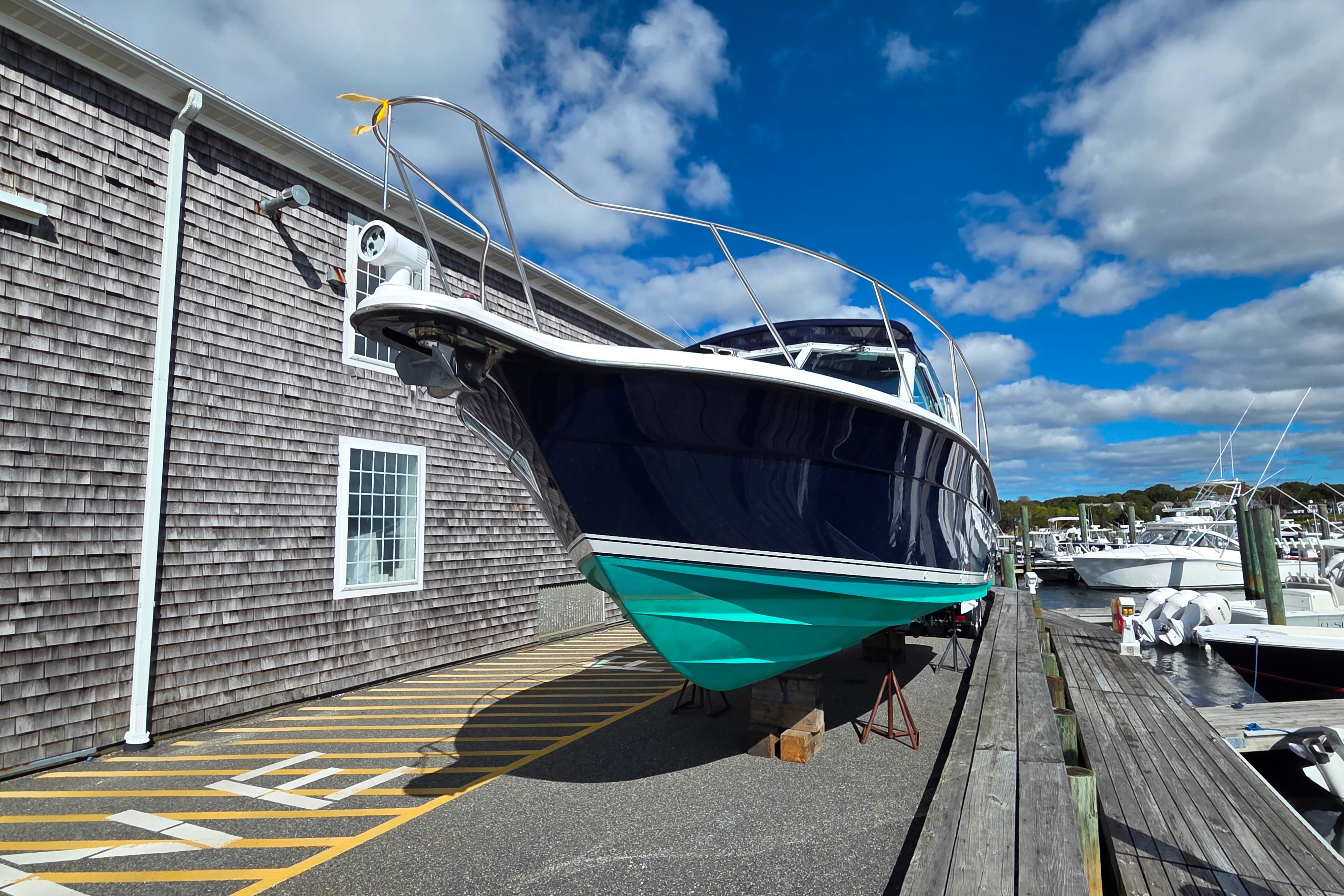 2004 Tiara 29 Coronet Harbor Edition boat docked near wooden building under blue sky.