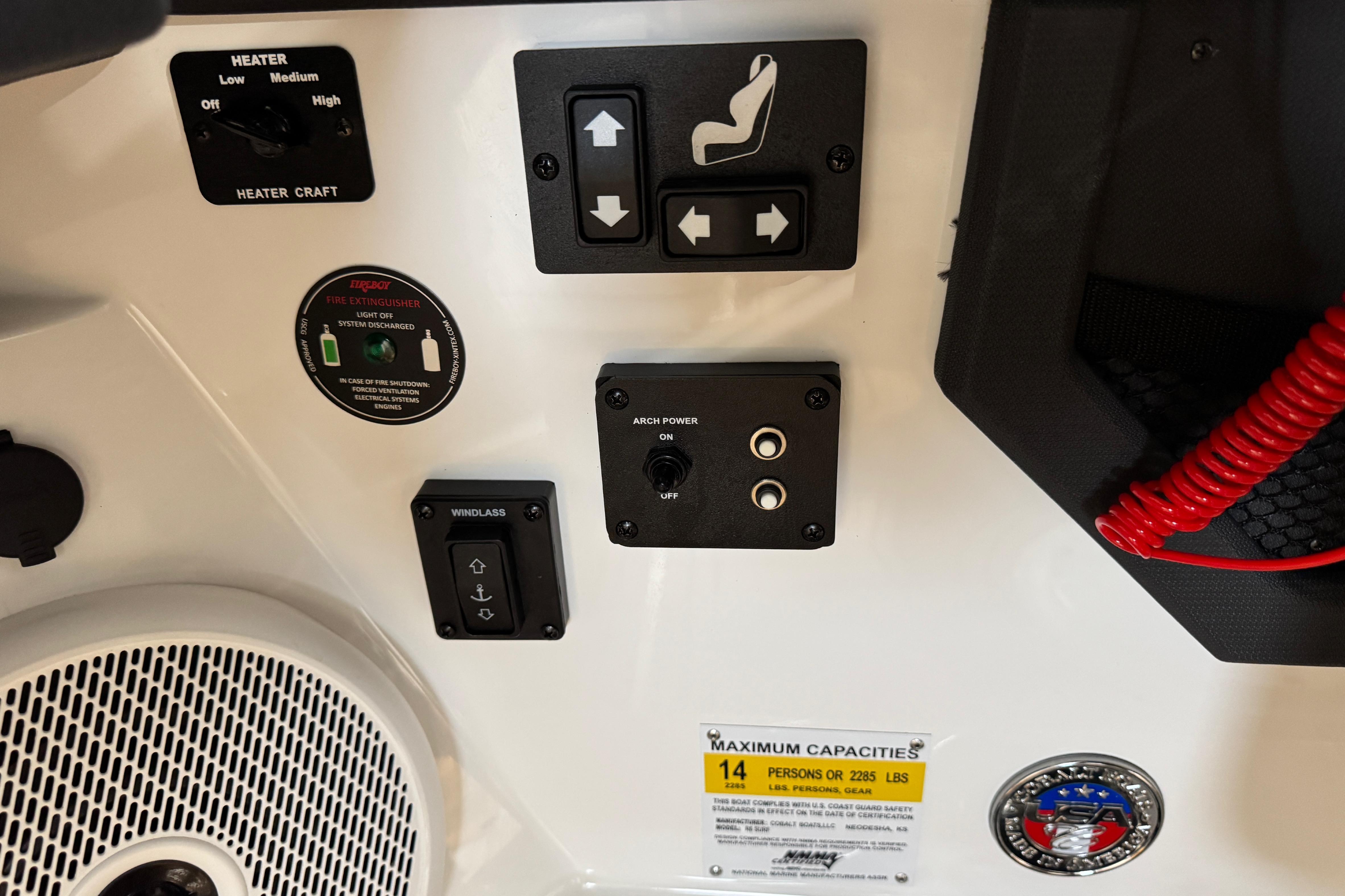 Control panel of 2023 Cobalt R6 Surf boat with various switches and capacity label.