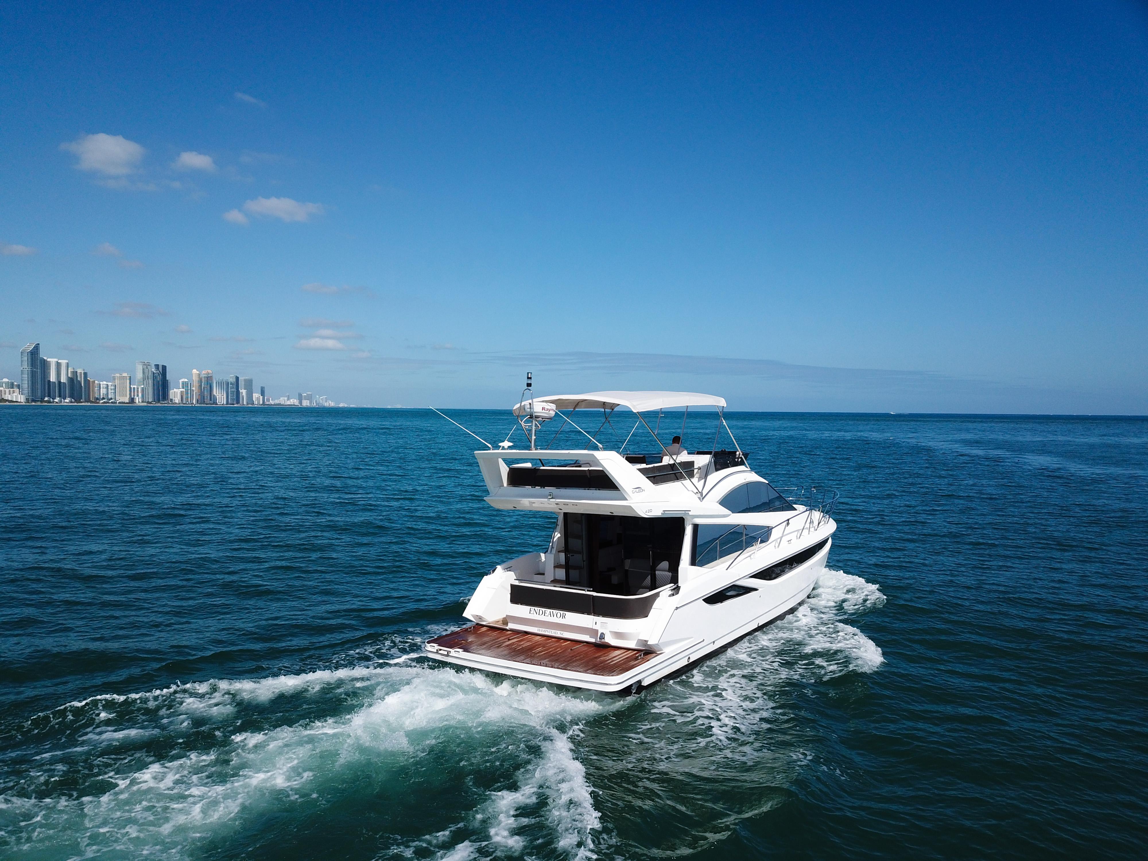 2016 Galeon 420 Fly yacht cruising on open sea near city skyline.