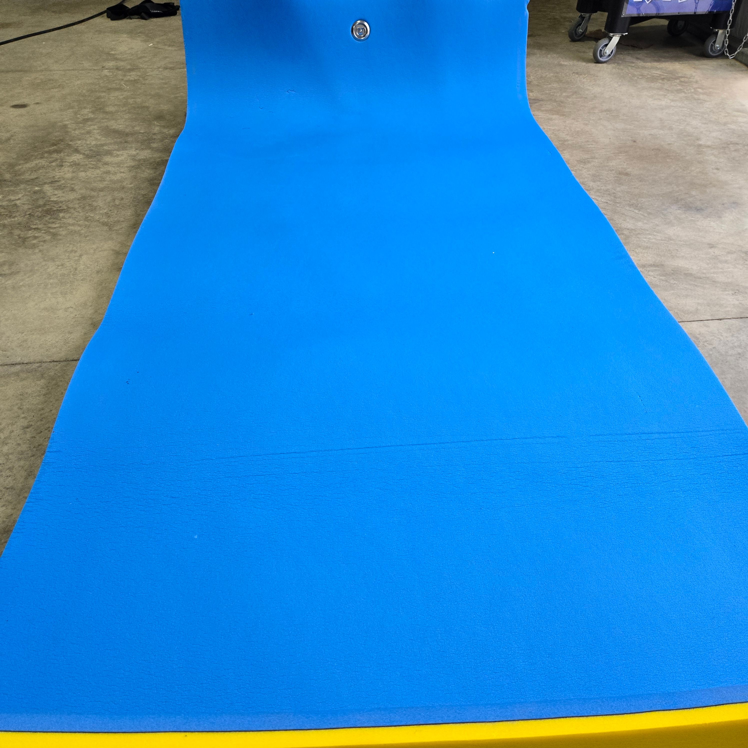 A boat with a bright blue mat on the deck, parked in a garage.