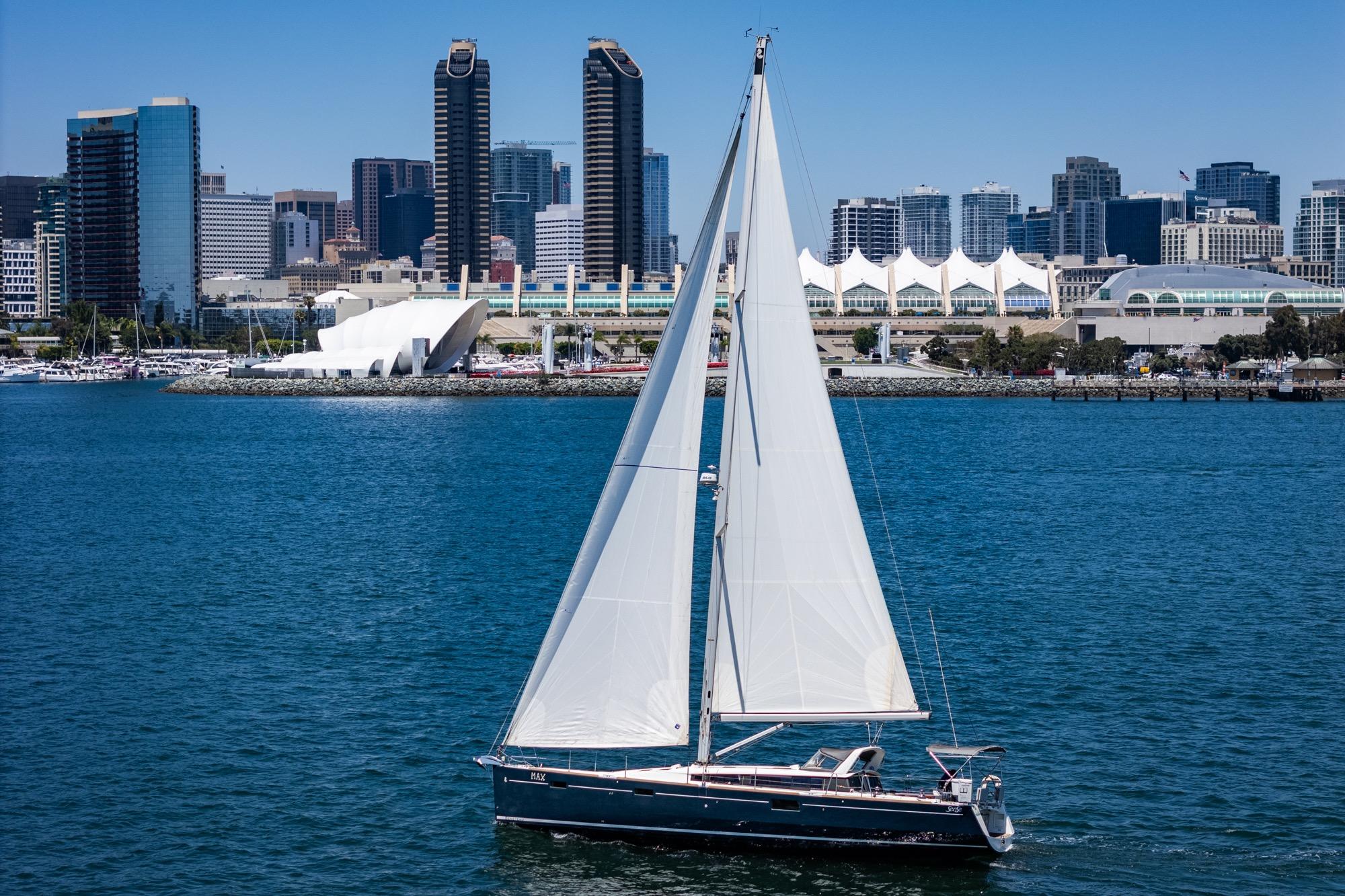 Sailing yacht Beneteau Sense 50, 2017, cruising near urban skyline and waterfront.
