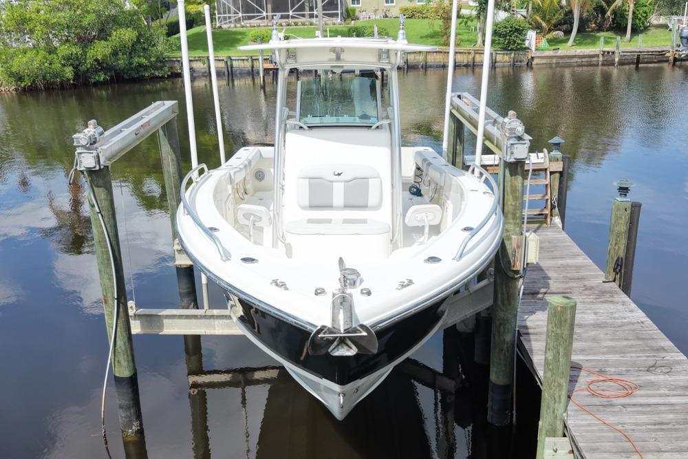 2018 Mako 284 Center Console boat docked on a lift by a calm river.