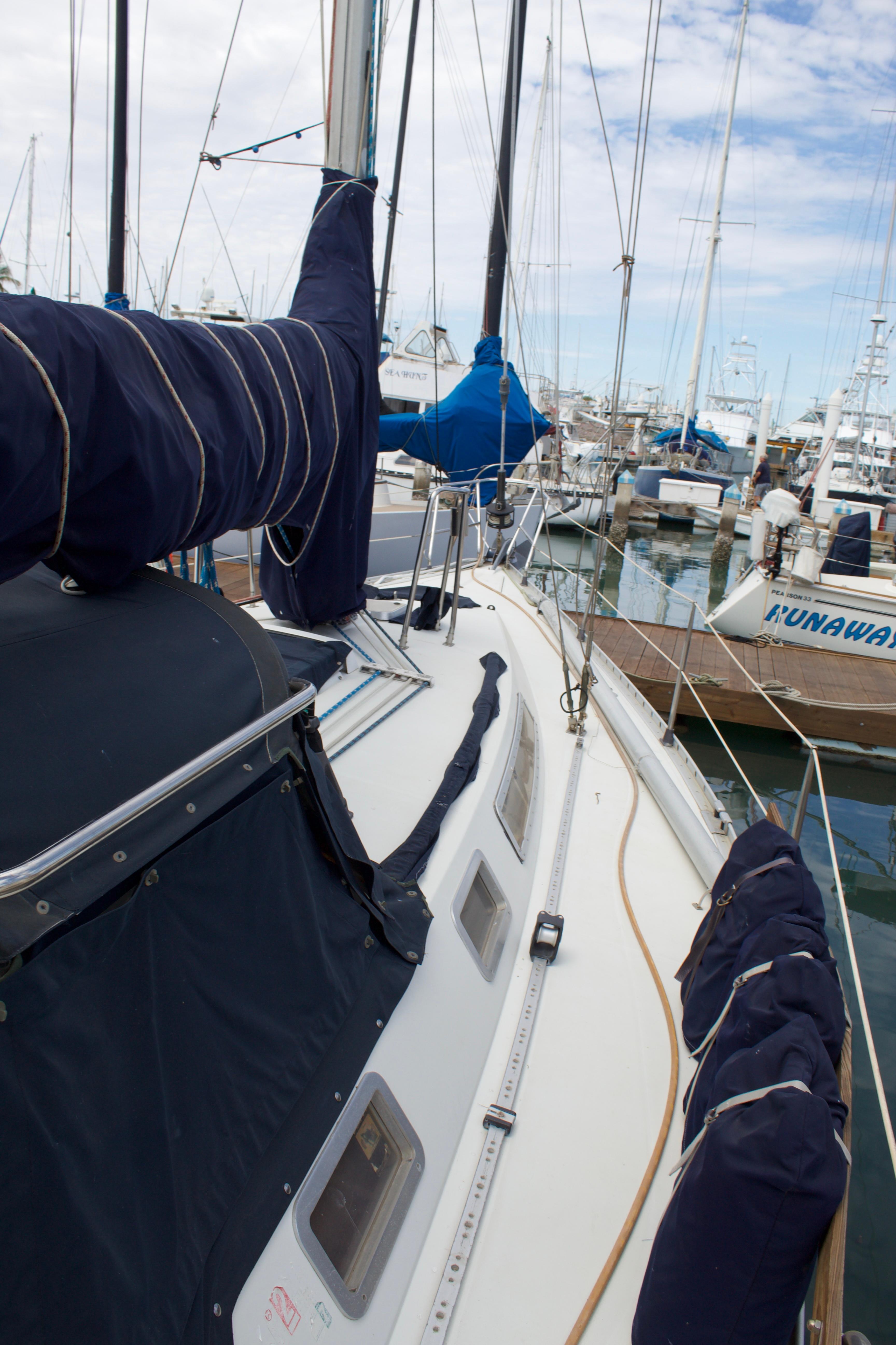 1988 Beneteau First 405 Tall Rig sailboat docked in marina, featuring covered sails and clear sky.