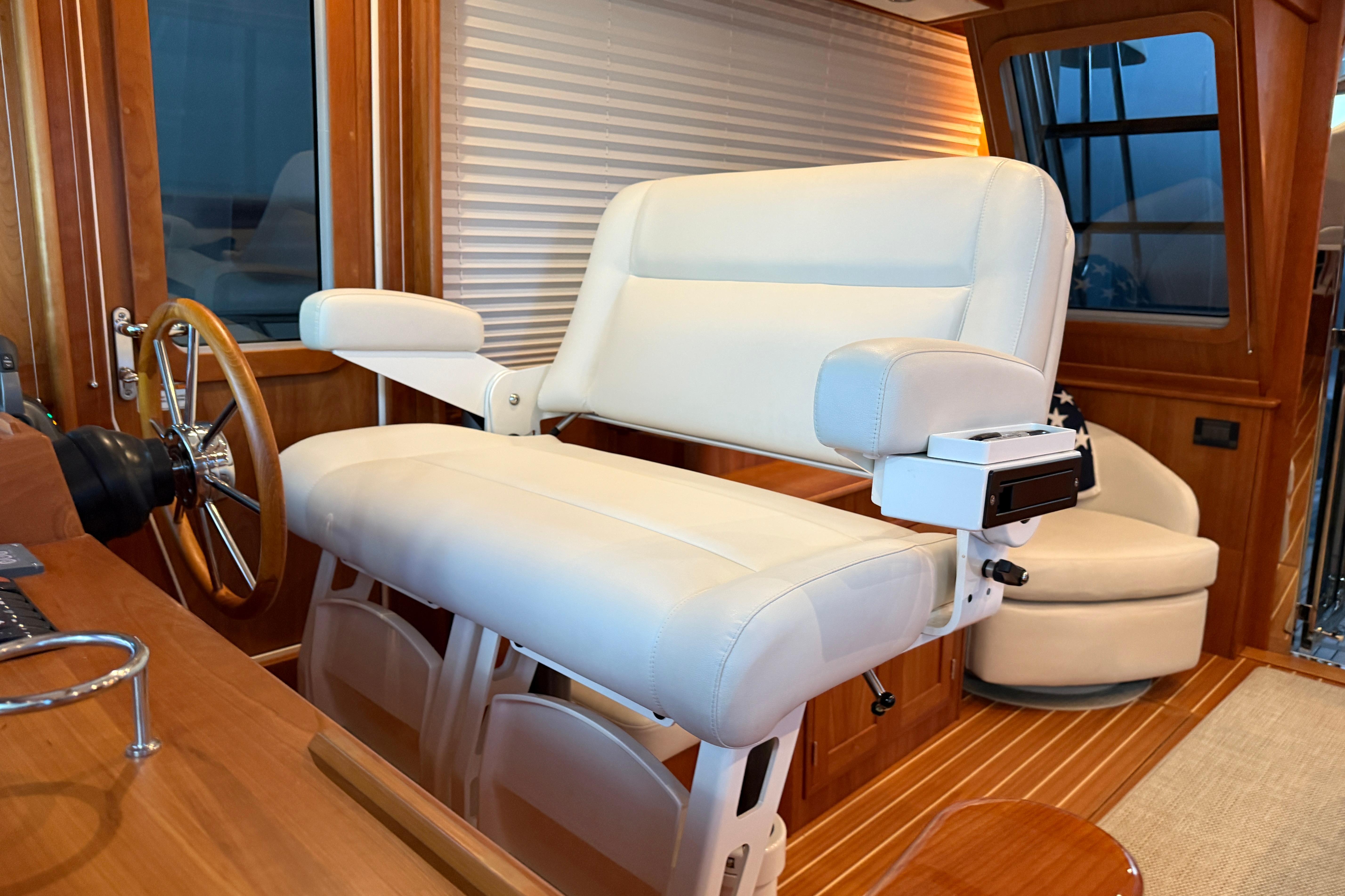 Captain's chair on 2021 Sabre 42 Fly Bridge, featuring luxurious white upholstery and wooden accents.