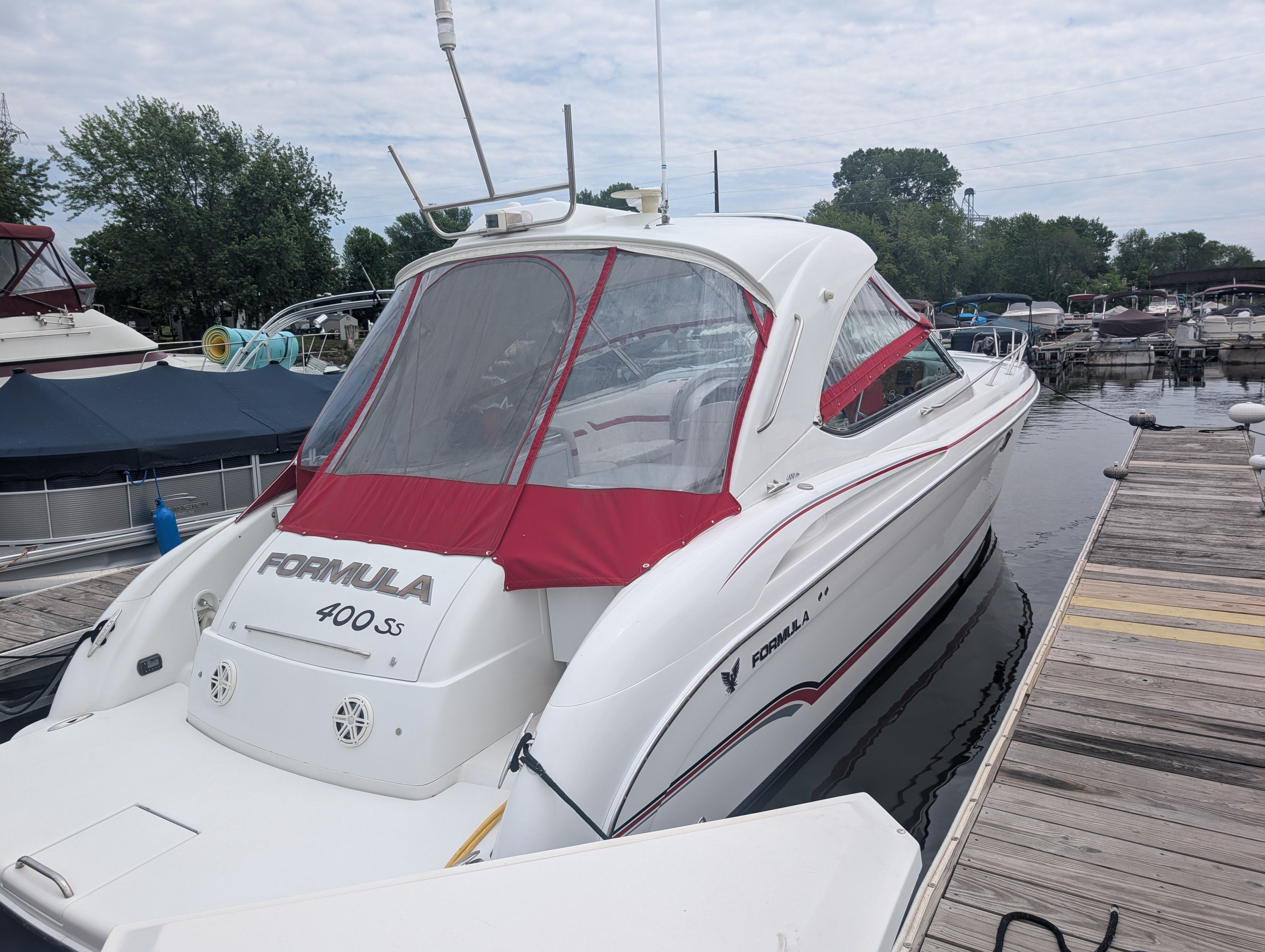 A white motorboat with a red canopy docked. It's a 2007 Formula 400 Super Sport.