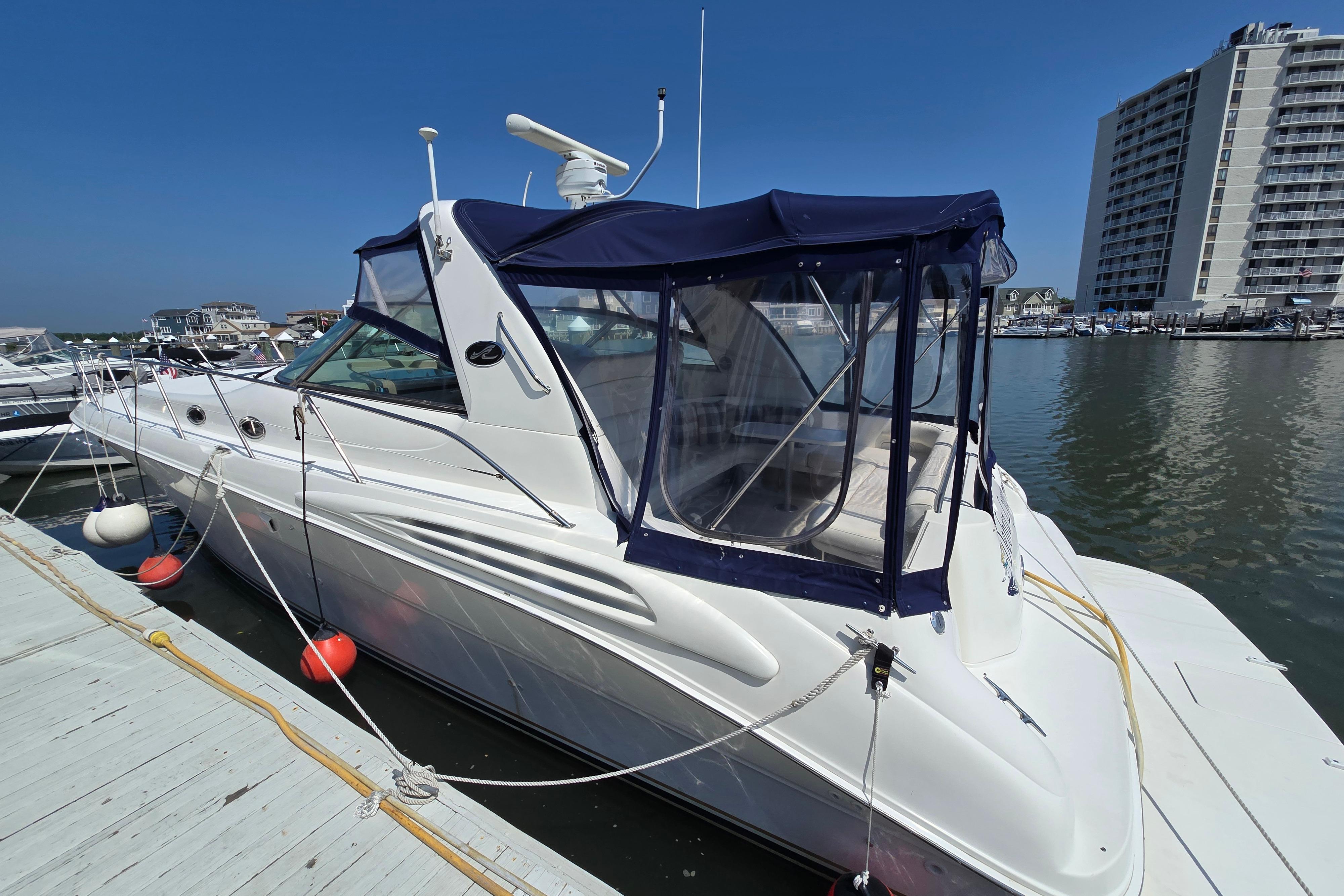 1999 Sea Ray Sundancer 400 yacht docked at marina, featuring blue canopy and sleek design.