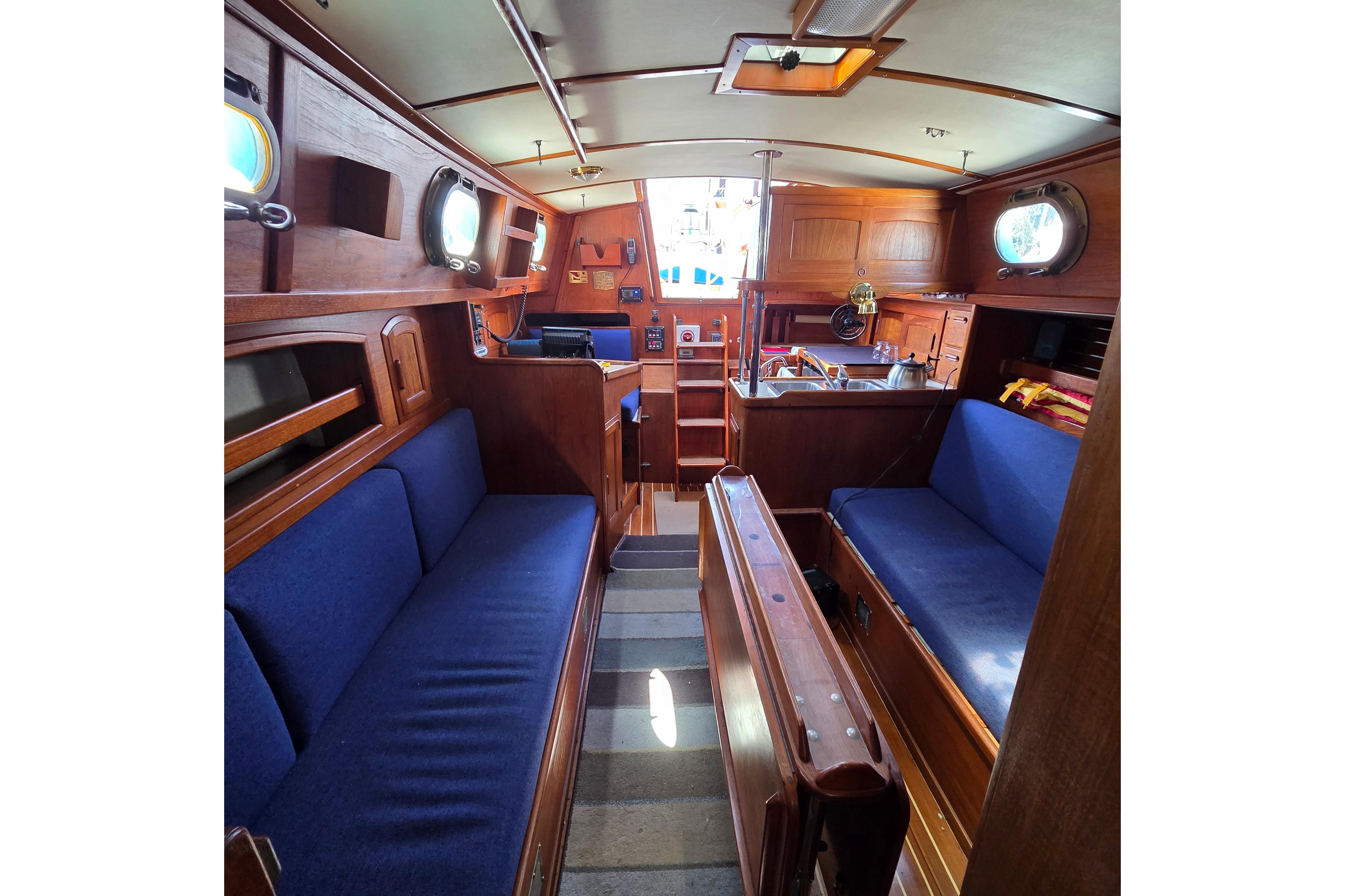 Interior of 1983 Pacific Seacraft 34 sailboat with wooden finish and blue seating.