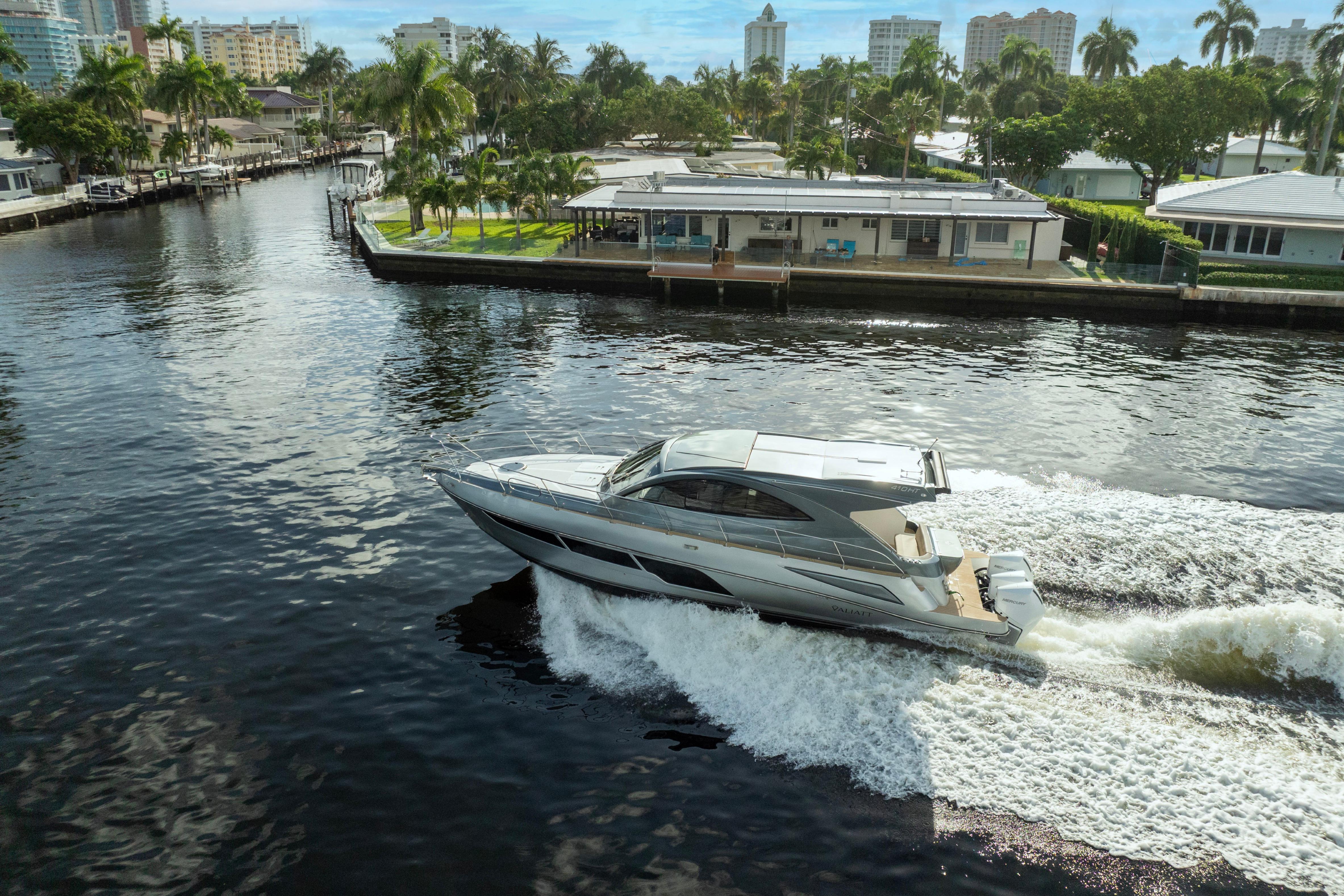 2025 Valiatt 410HT yacht cruising on a scenic waterway with palm trees and buildings.