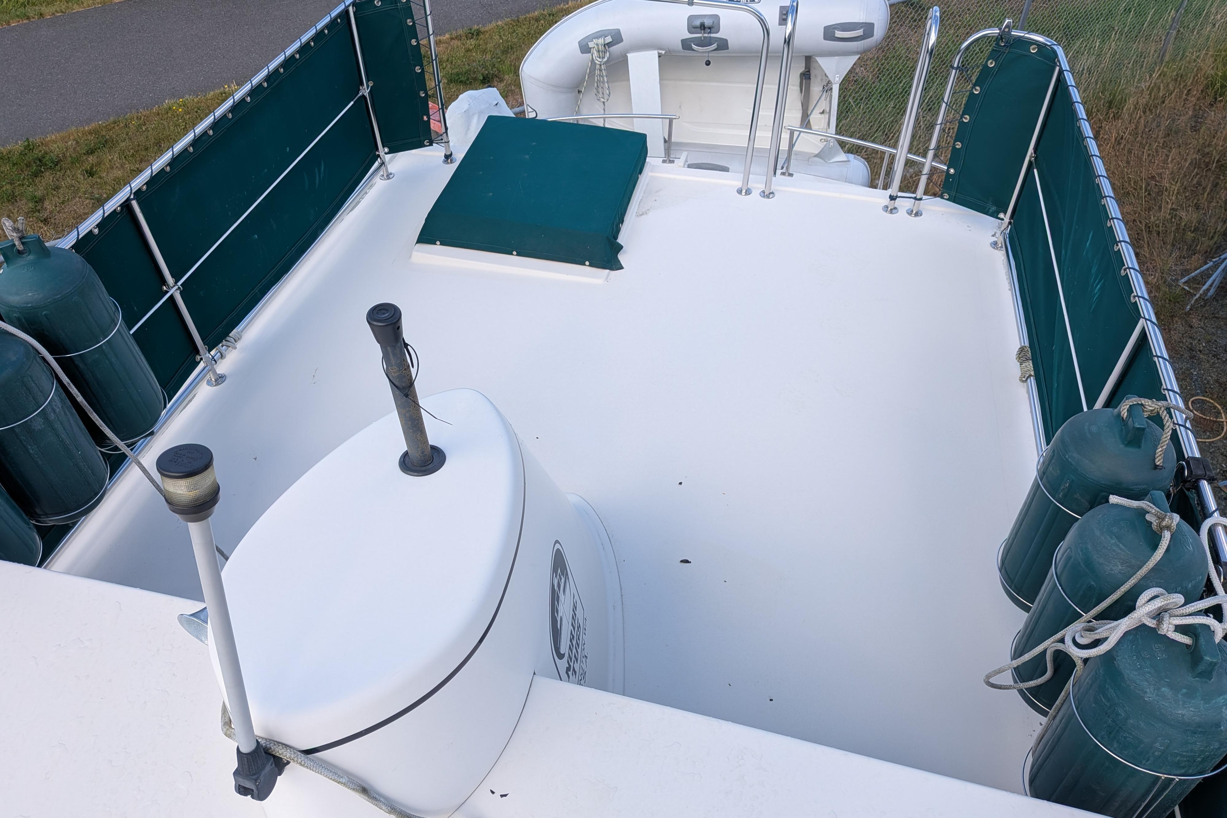 1998 Nordic Tug 32 boat deck with green fenders and railing, featuring a clean white surface.
