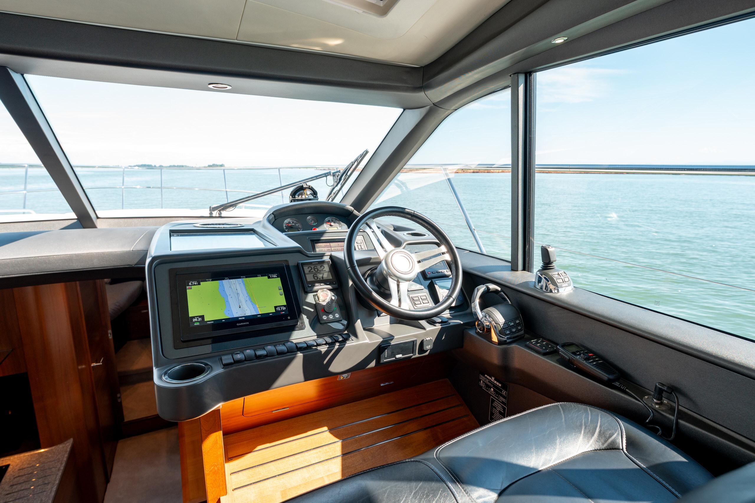 Interior view of 2015 Princess V48 yacht cockpit with navigation system and steering wheel.