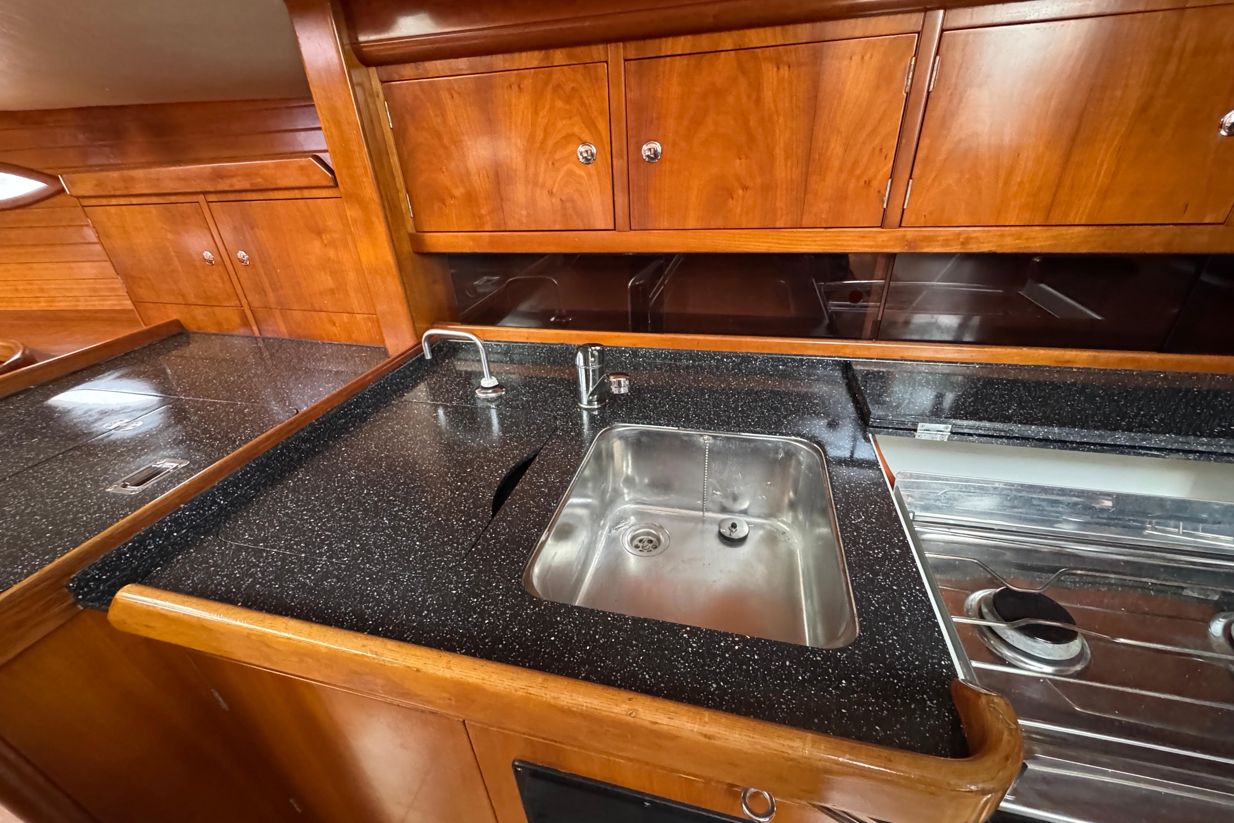 Luxurious 2004 Alliaura FEELING 44 DI yacht kitchen with sleek wood cabinetry and modern sink.